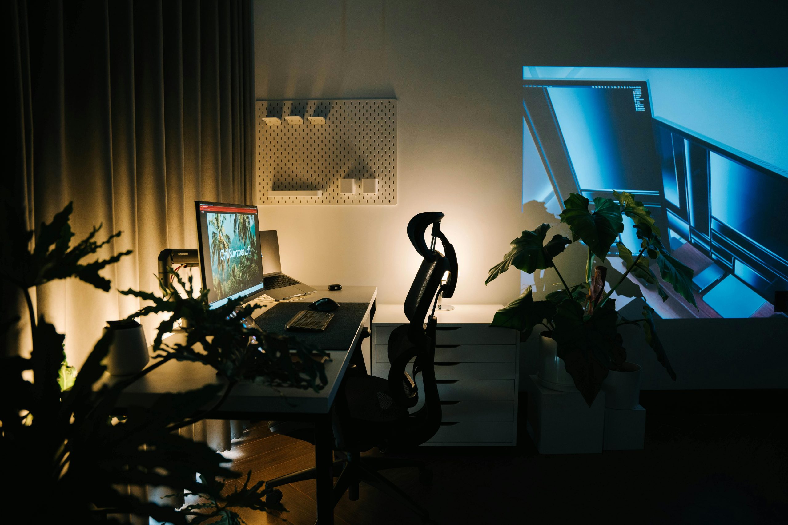 A cozy home office setup featuring ambient lighting, plants, and a computer workspace.