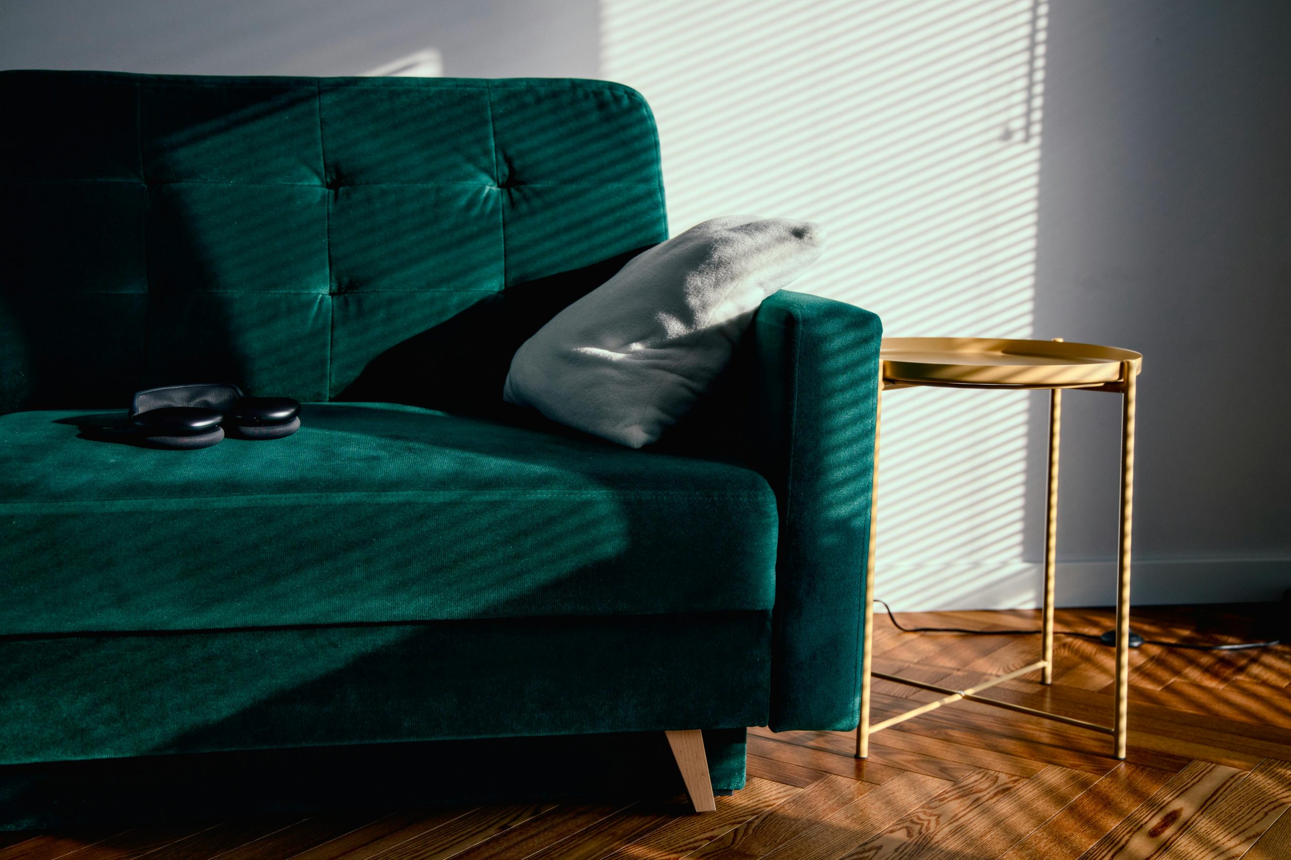 A serene living room featuring a sunlit green velvet sofa and modern minimal decor.