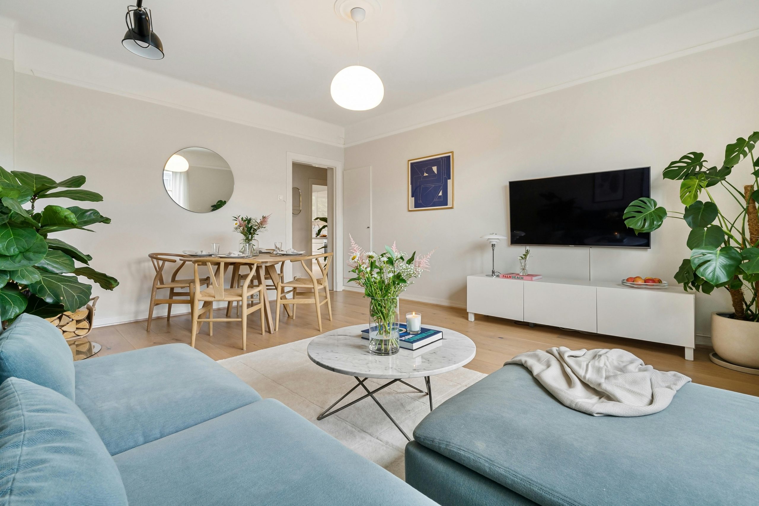 A stylish and bright living room with modern furnishings and plants, exuding a minimalist vibe.