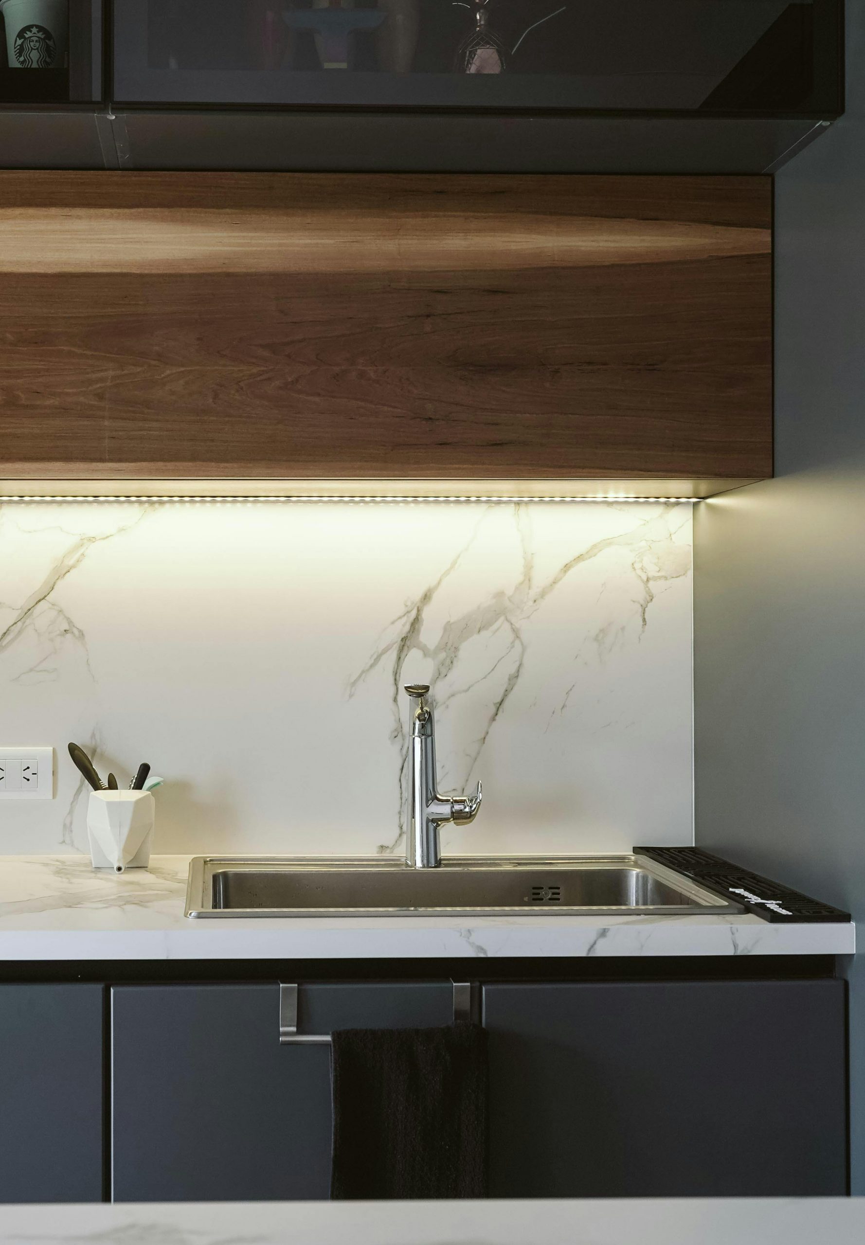 A stylish modern kitchen featuring a sleek faucet, marble surfaces, and minimalist design.