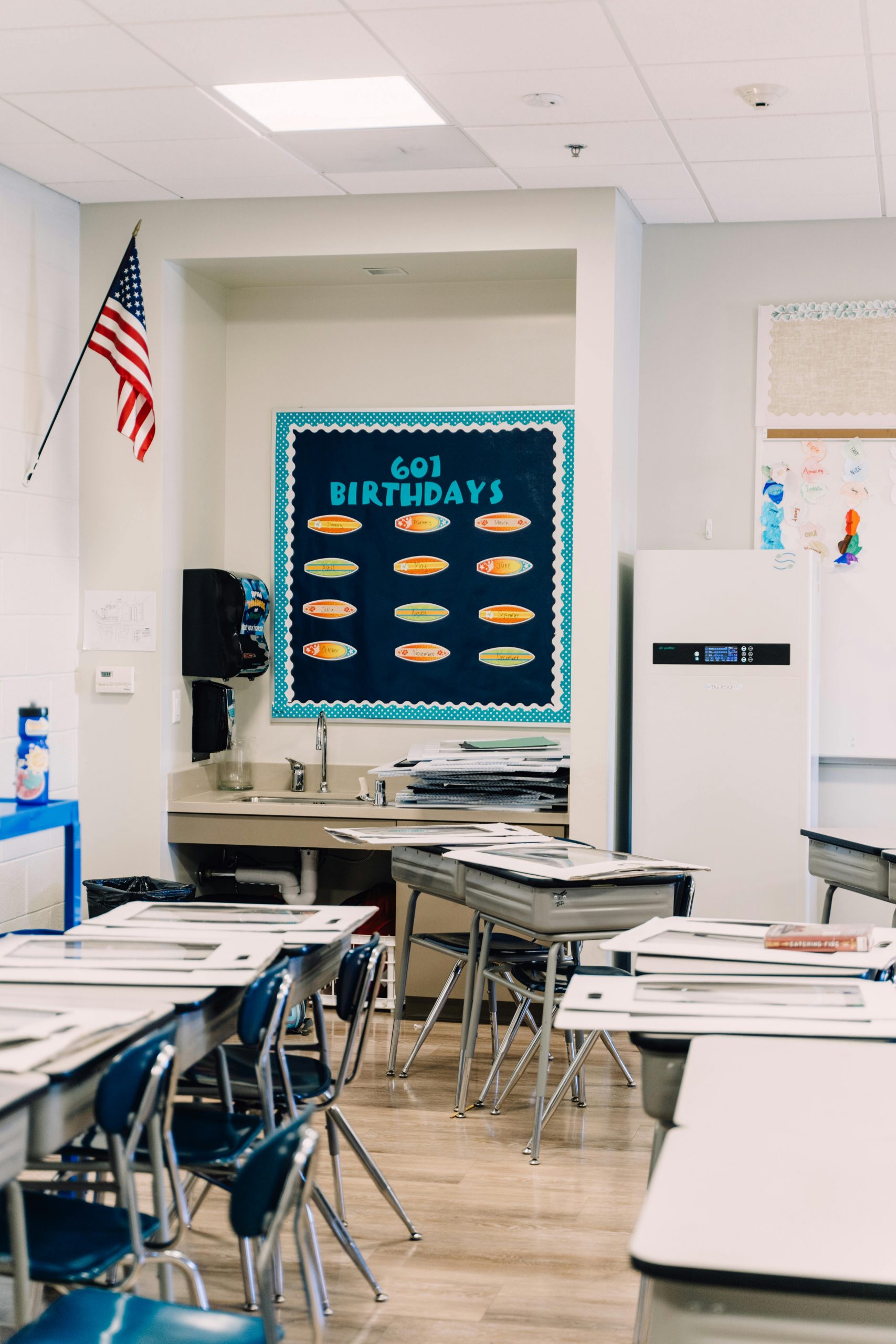 A well-lit classroom with desks, chairs, and a birthday board. Perfect for educational themes.