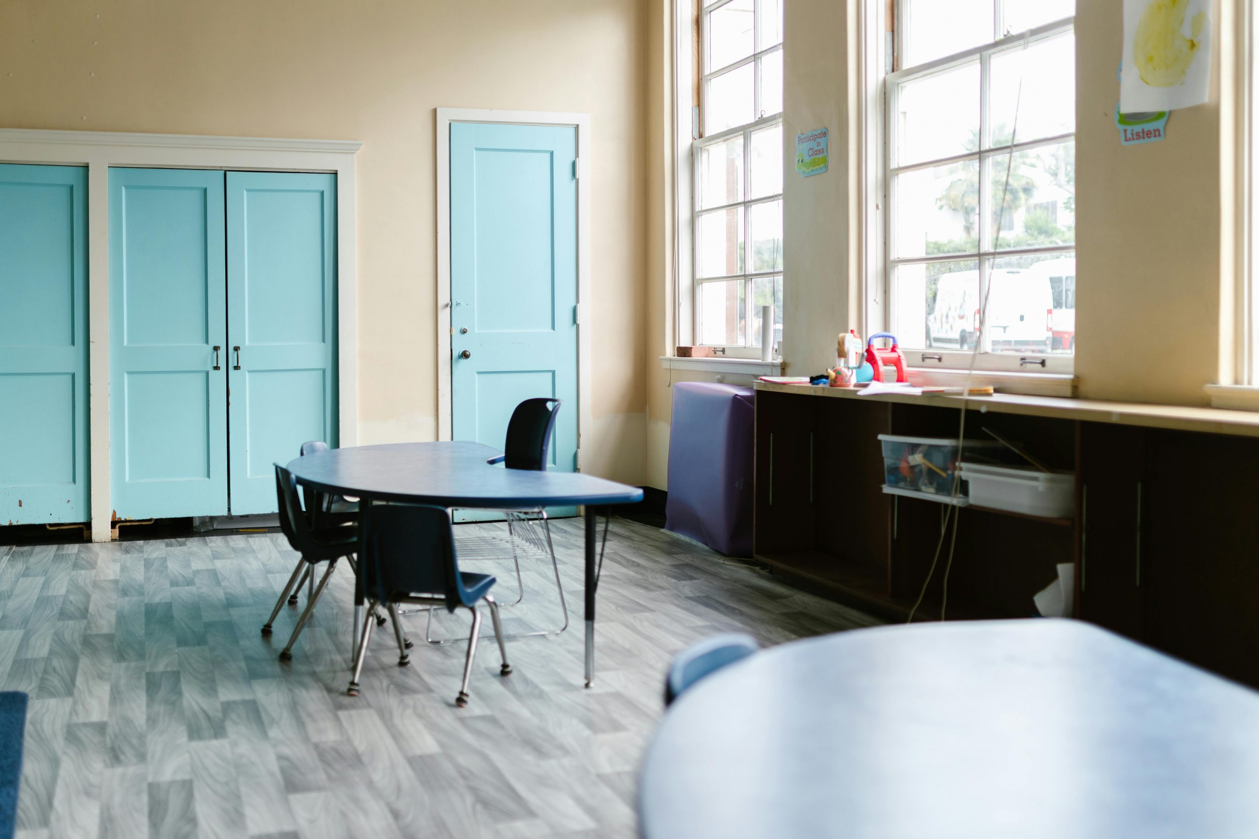 A well-lit empty classroom with blue doors and desks, ideal for education themes.