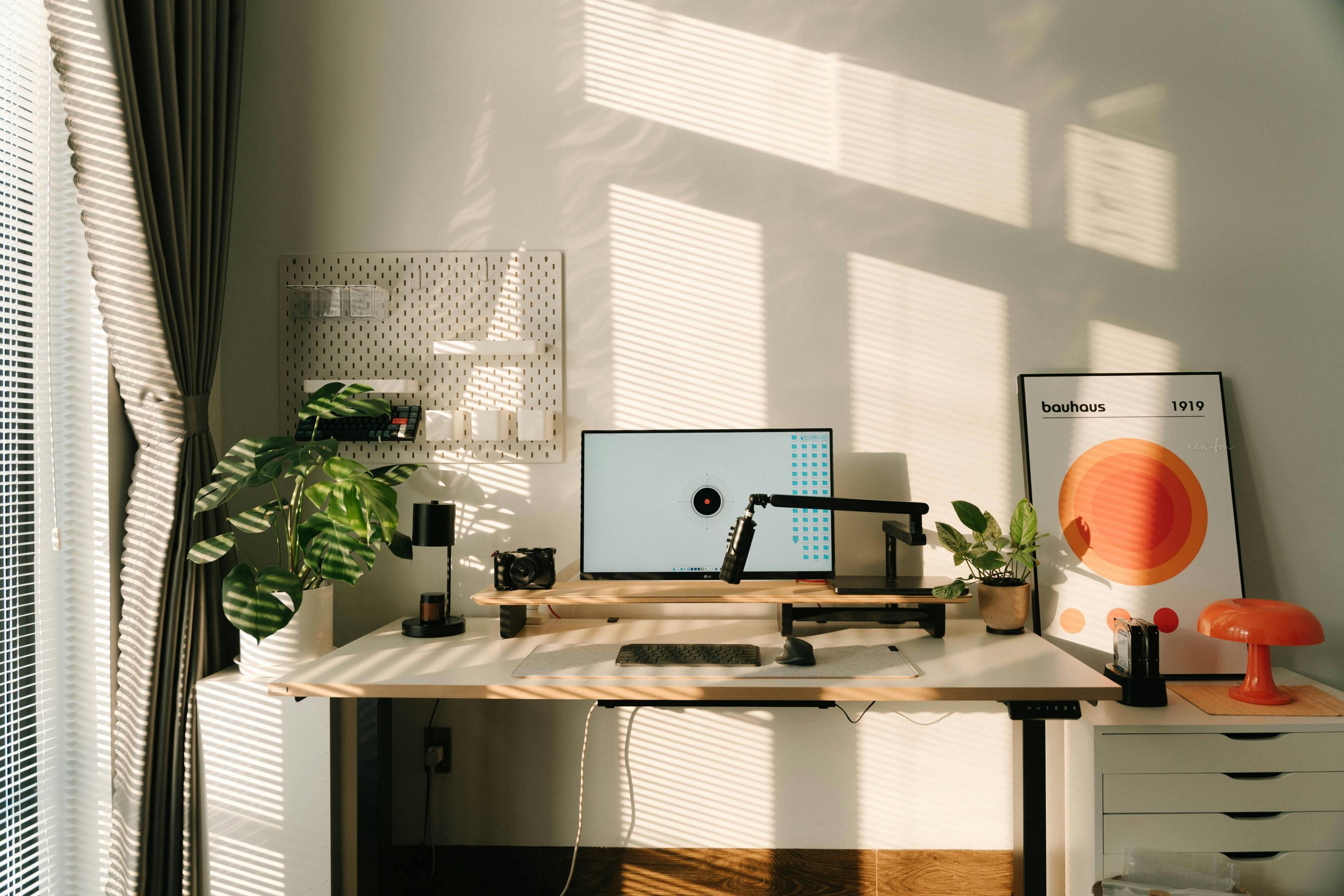 A well-lit minimalist home office desk setup with modern decor and vibrant plants.