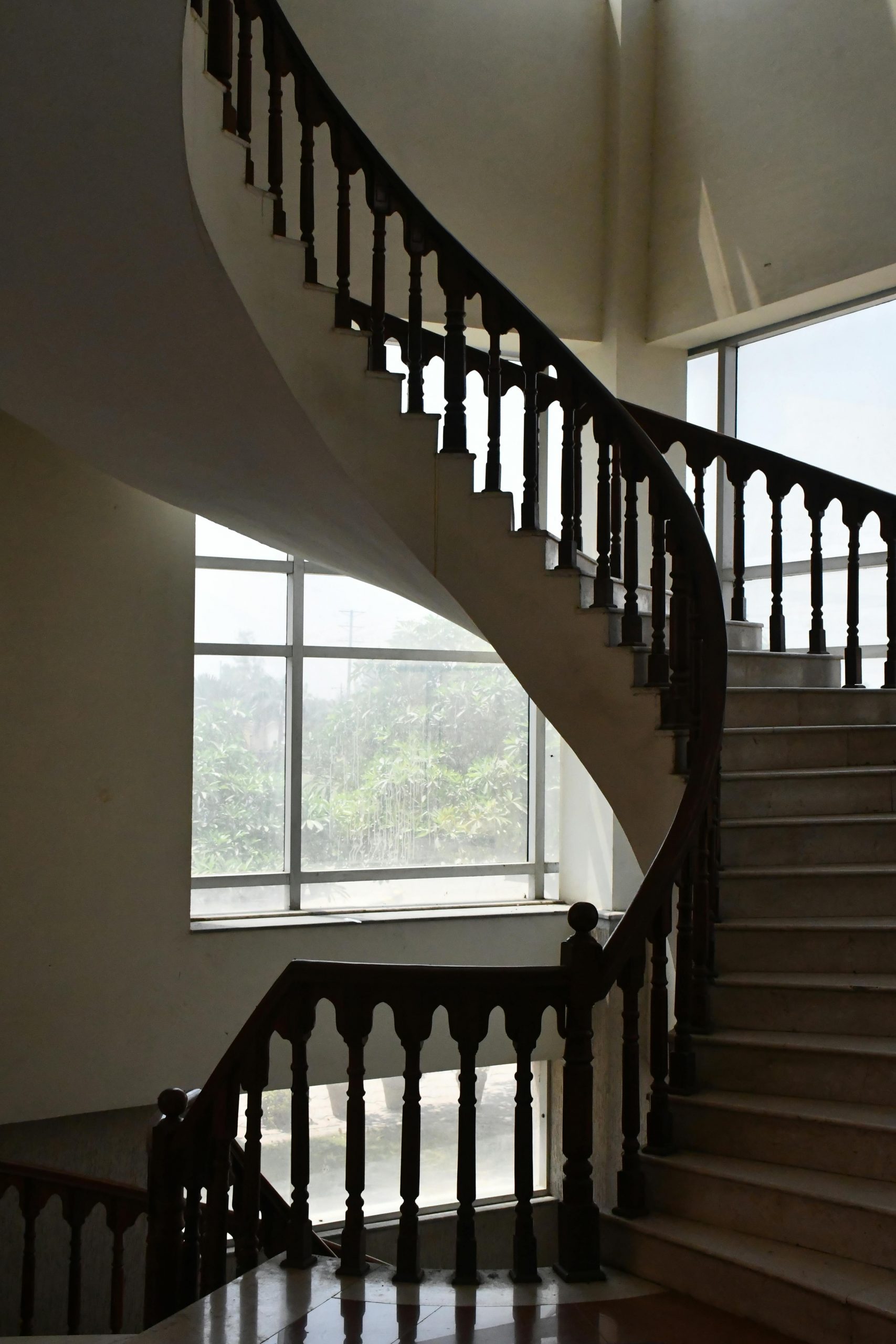 An elegant curved staircase in a sunlit interior showcasing classic architectural design in Faisalabad.