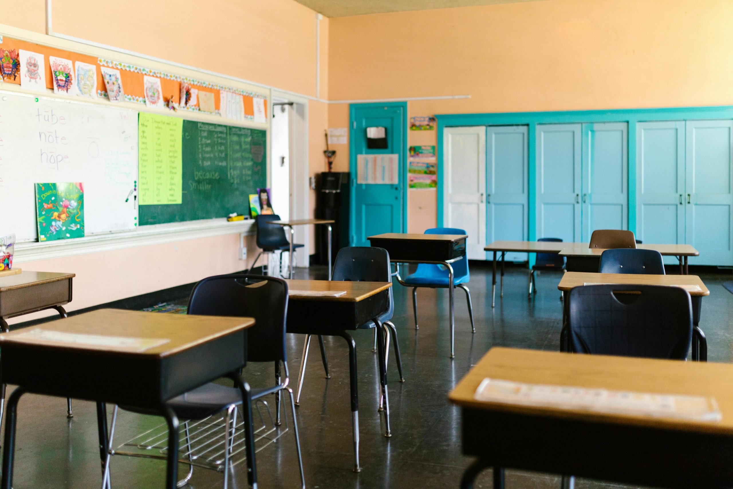 Bright and colorful empty classroom with desks, blackboard, and educational materials.
