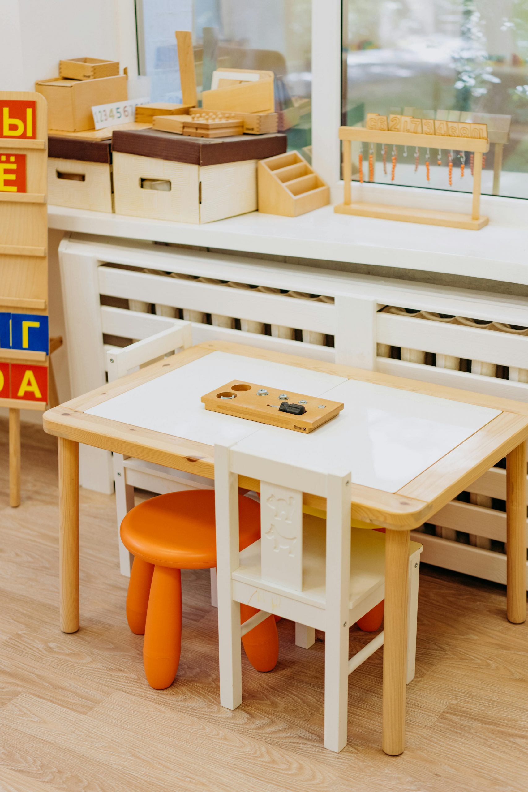 Bright kindergarten classroom featuring a wooden table, chairs, and educational toys.