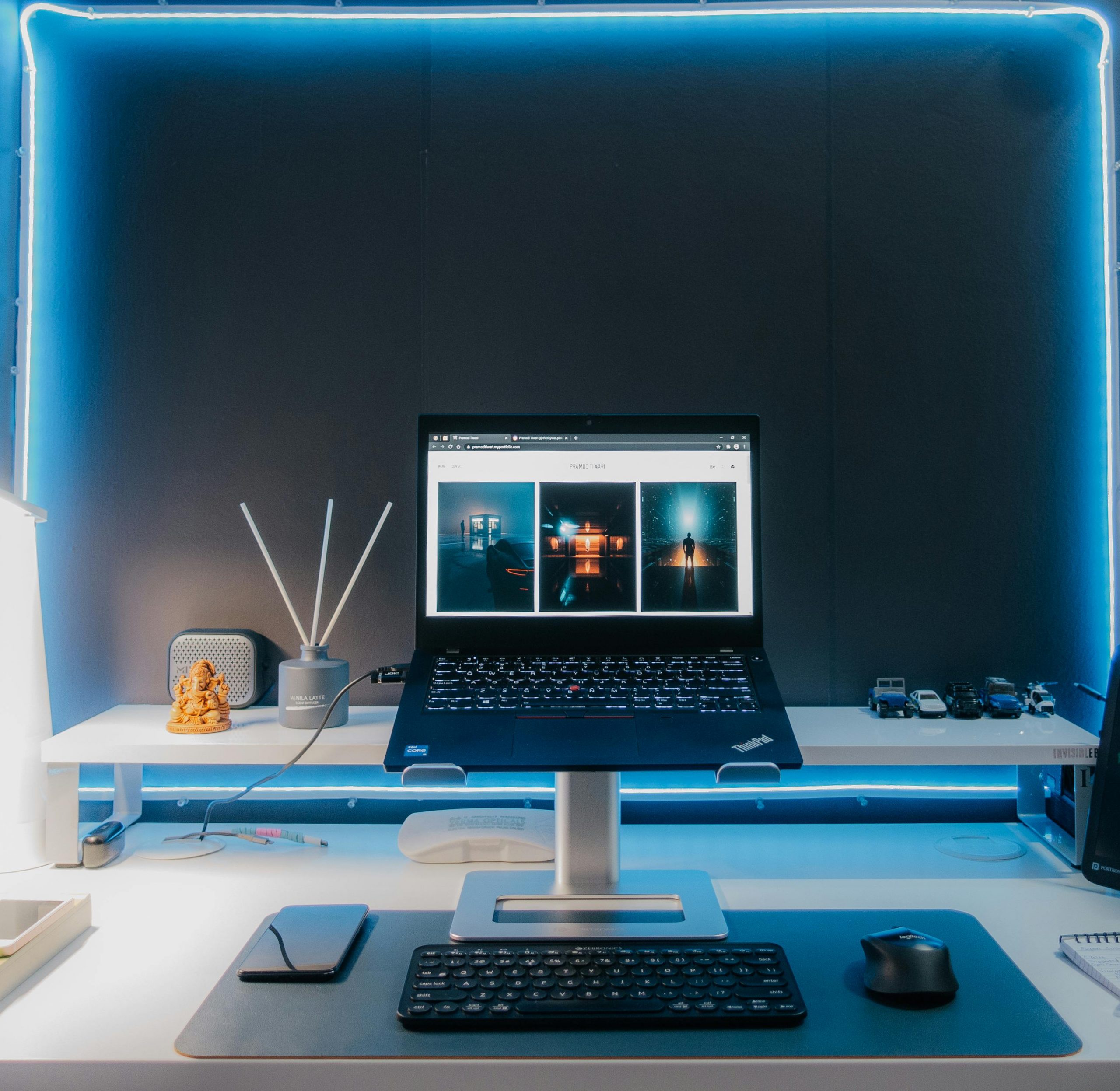 Contemporary desk setup featuring a laptop, electronic accessories, and neon lighting for a stylish workspace.