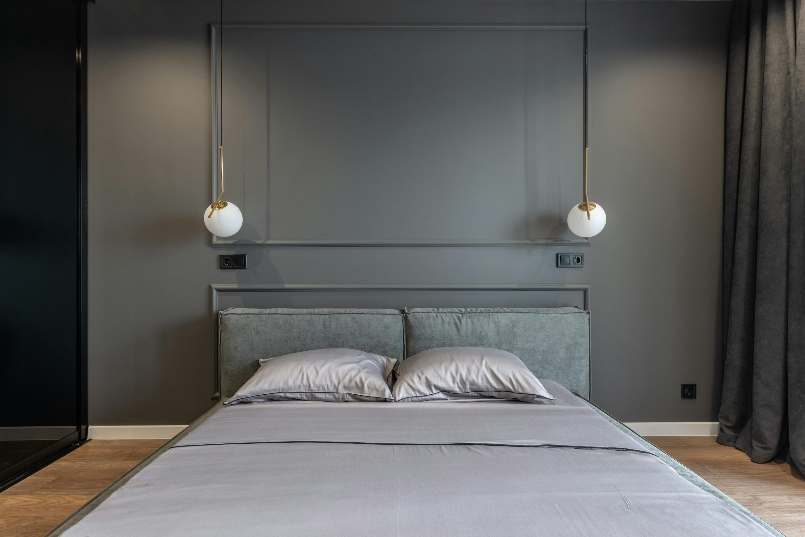 Contemporary minimalist style home interior design of bedroom in gray tones with pendant round lamps hanging above bed