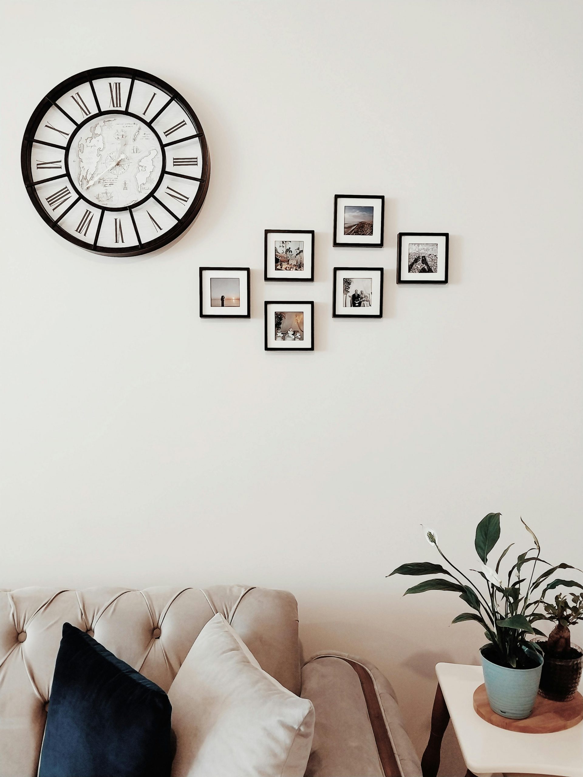Elegant living room interior featuring a large wall clock and framed photos on a minimalist wall.