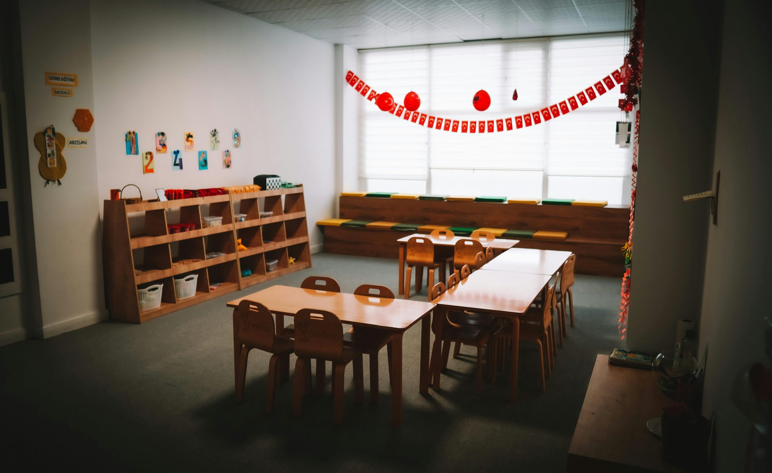Inviting kindergarten classroom with tables, chairs, and colorful decorations, fostering a welcoming learning environment.