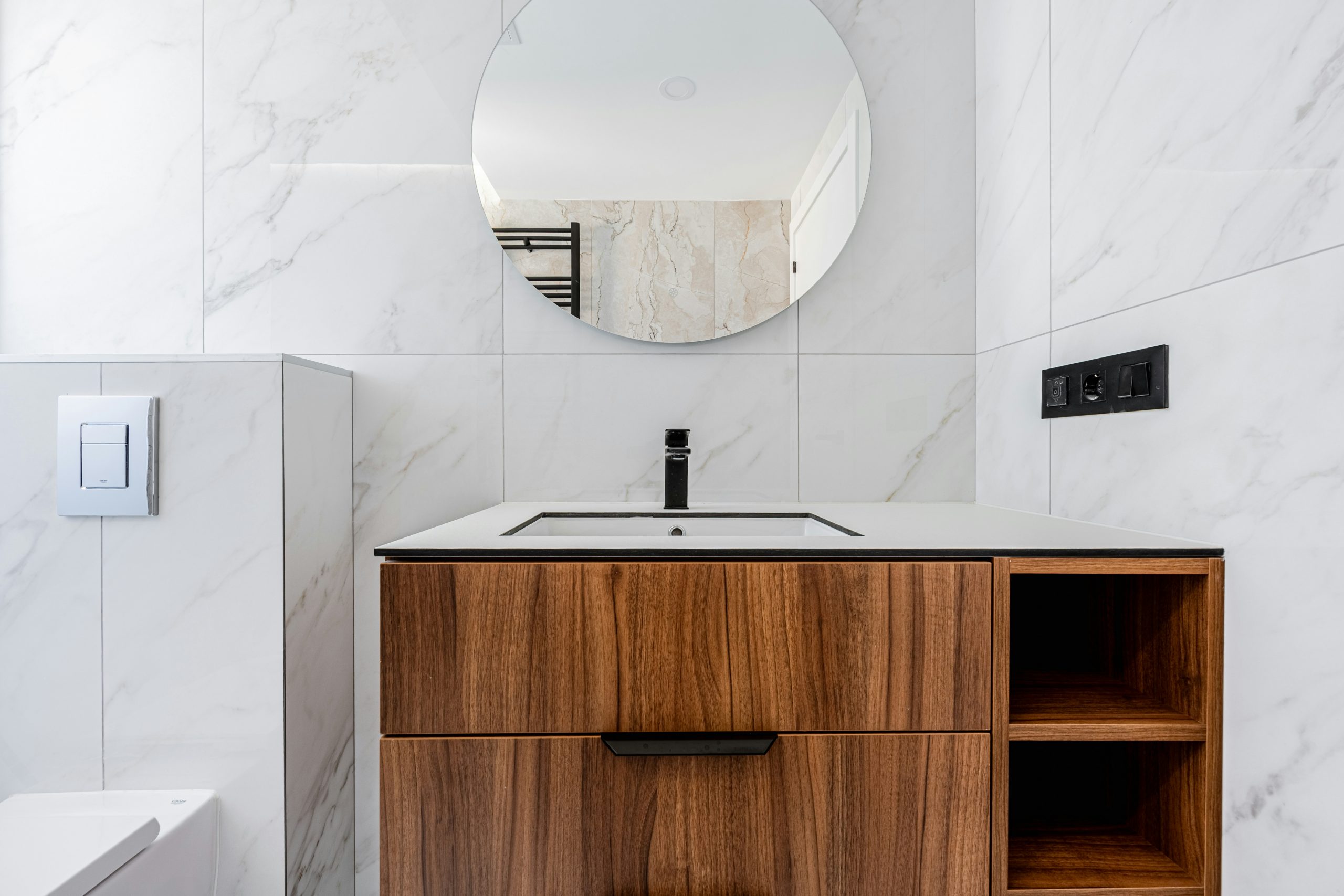 Luxury bathroom with round mirror and wooden vanity