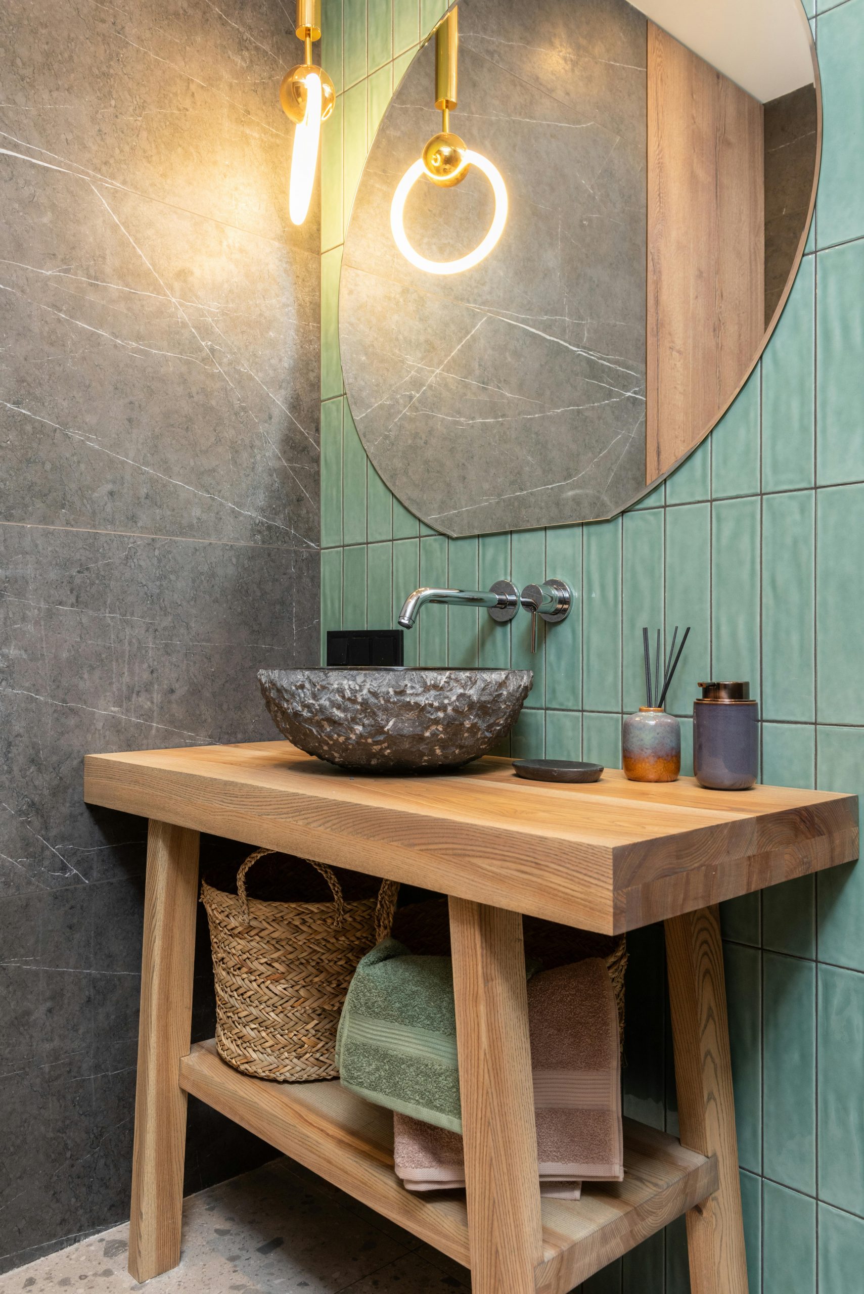 Minimalist bathroom design featuring a round mirror, stone washbasin, and unique pendant lighting.