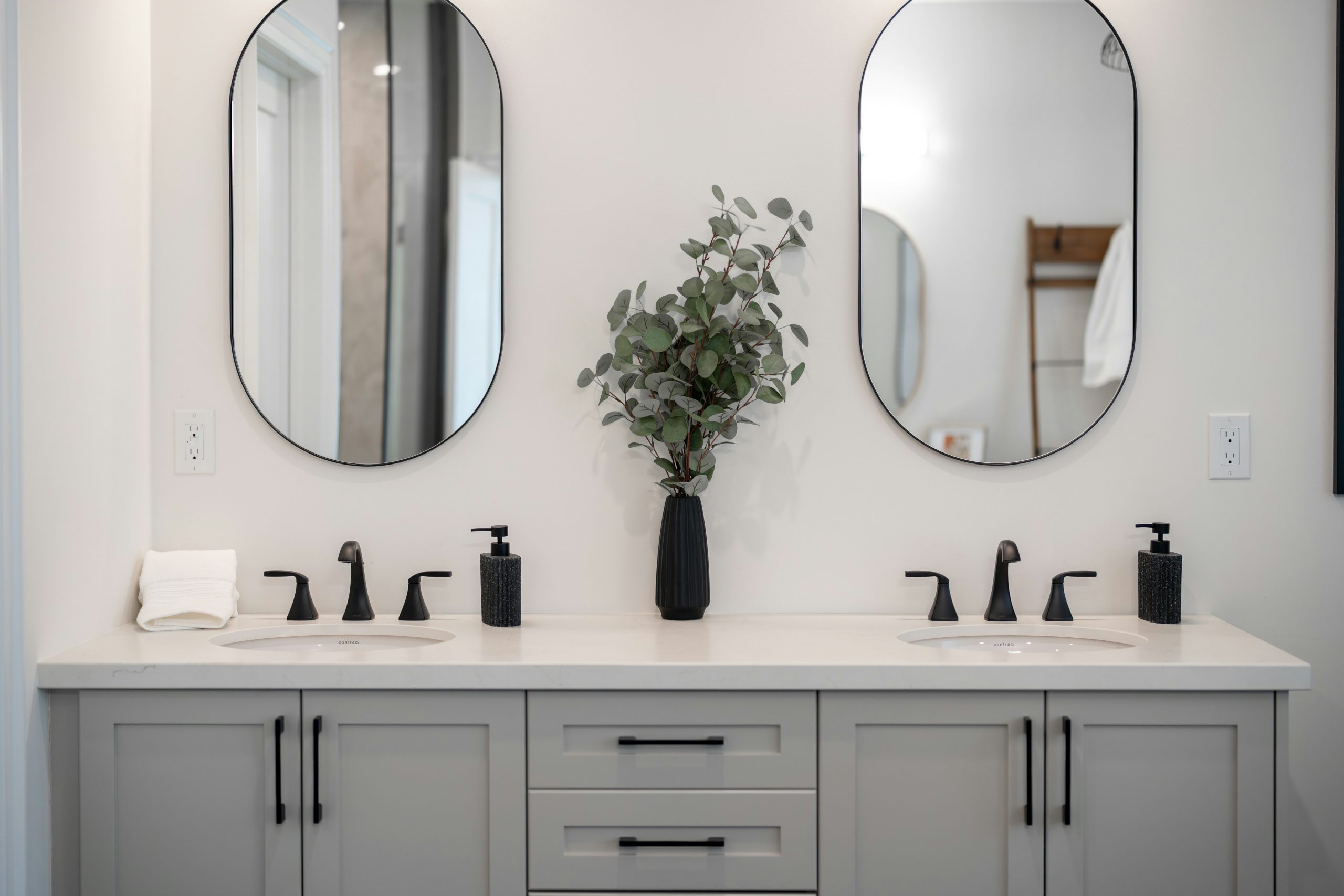Modern bathroom vanity with double sinks and mirrors.