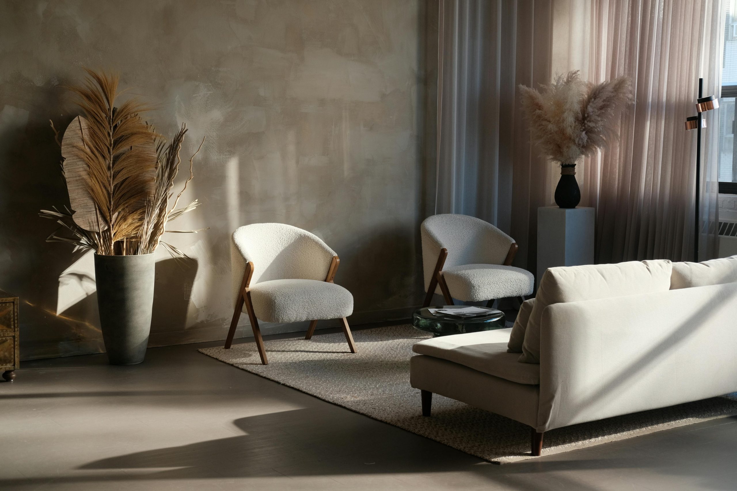 Moody Japandi style living room with pampas grass, textured walls, cozy seating, and soft lighting.