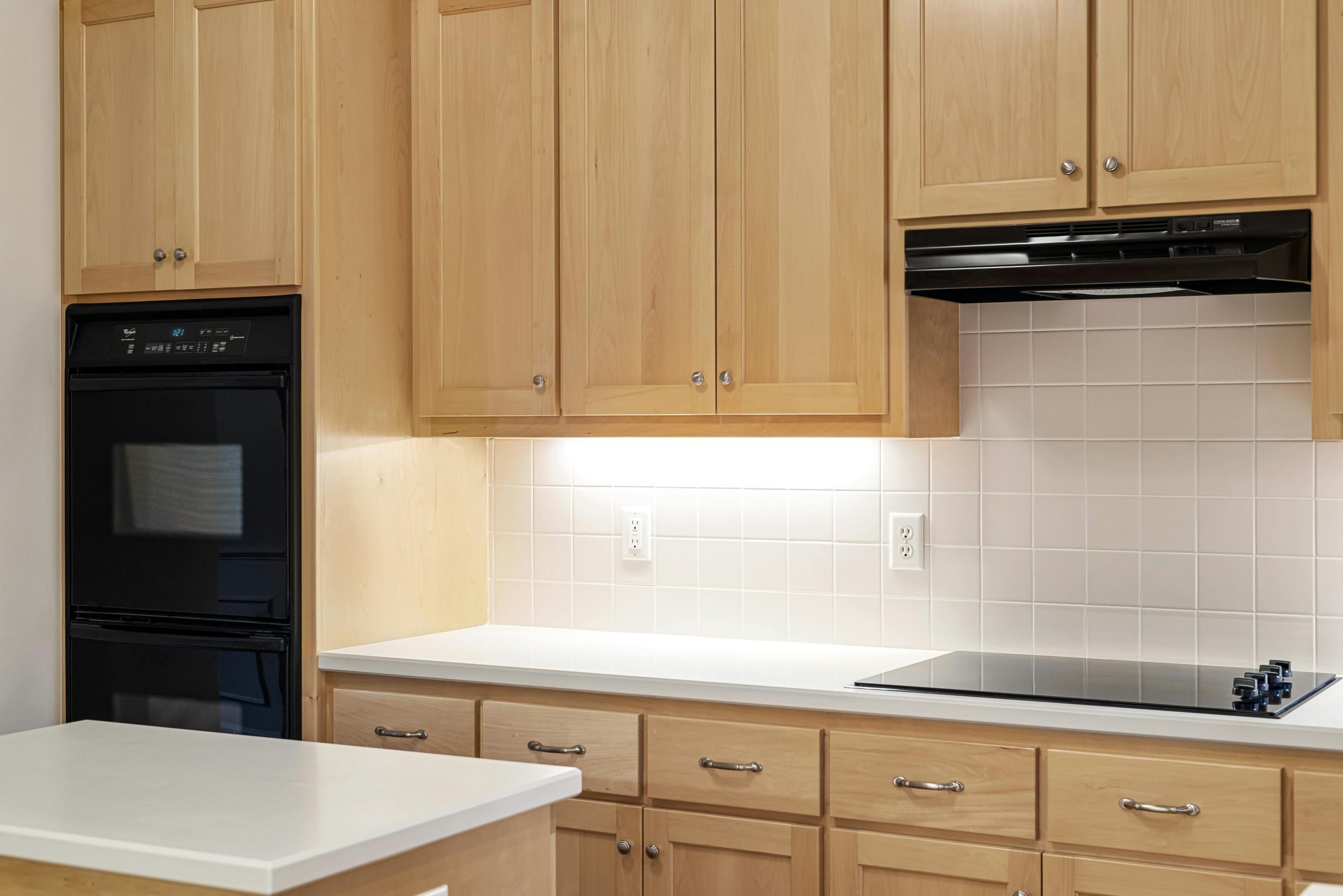 Sleek kitchen featuring wooden cabinets, black oven, and induction stove.