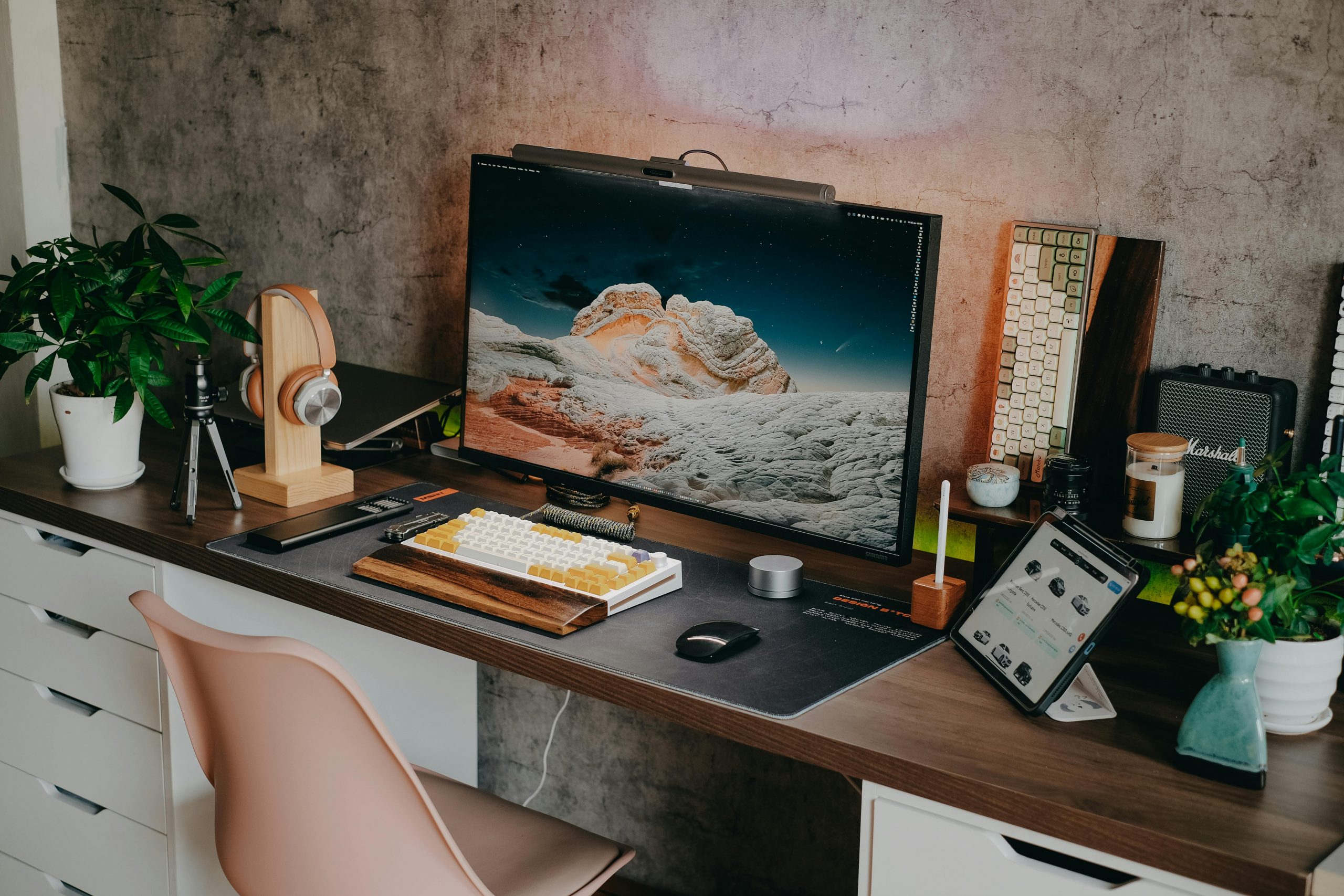 Stylish desk setup featuring a mechanical keyboard, monitor, plants, and tech gadgets.
