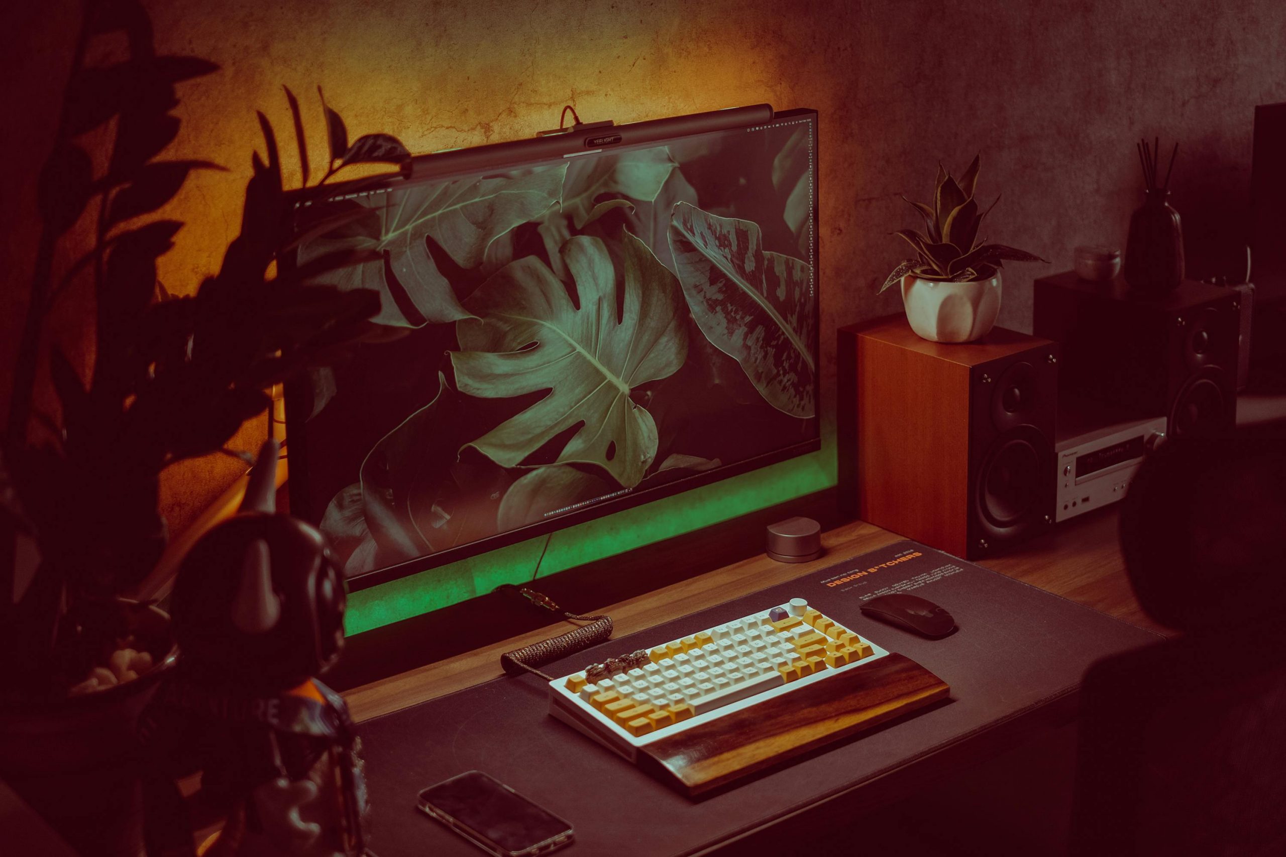 Stylish home office setup with a monitor, keyboard, and plants creating a cozy working environment.