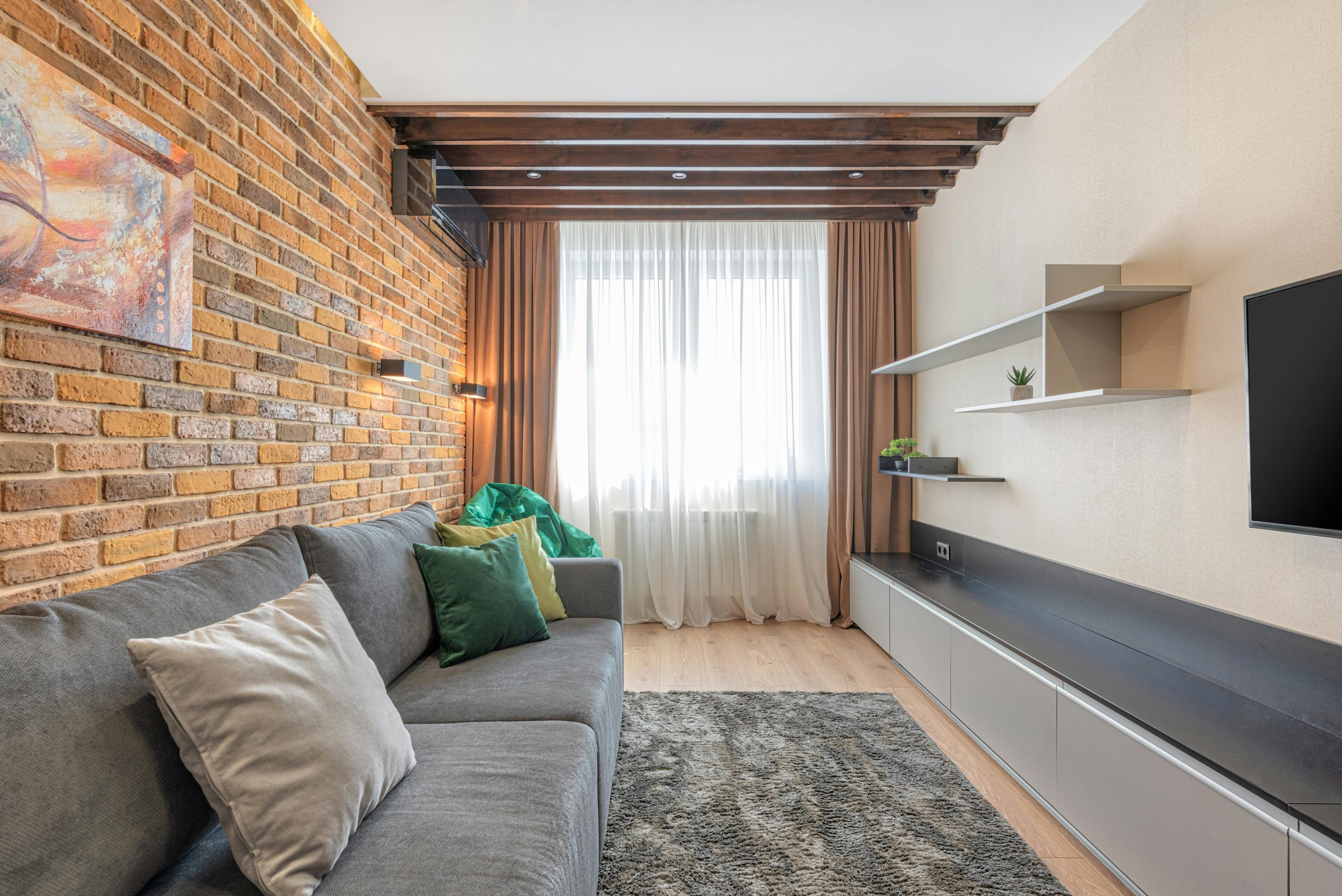 Stylish living room interior featuring a rustic brick wall, comfortable gray sofa, and elegant decor.