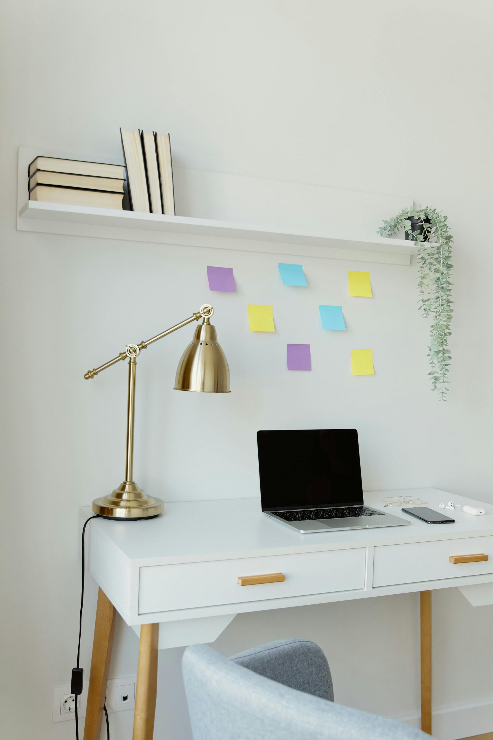 Stylish minimalist workspace featuring laptop, desk lamp, books, and decor for productivity.