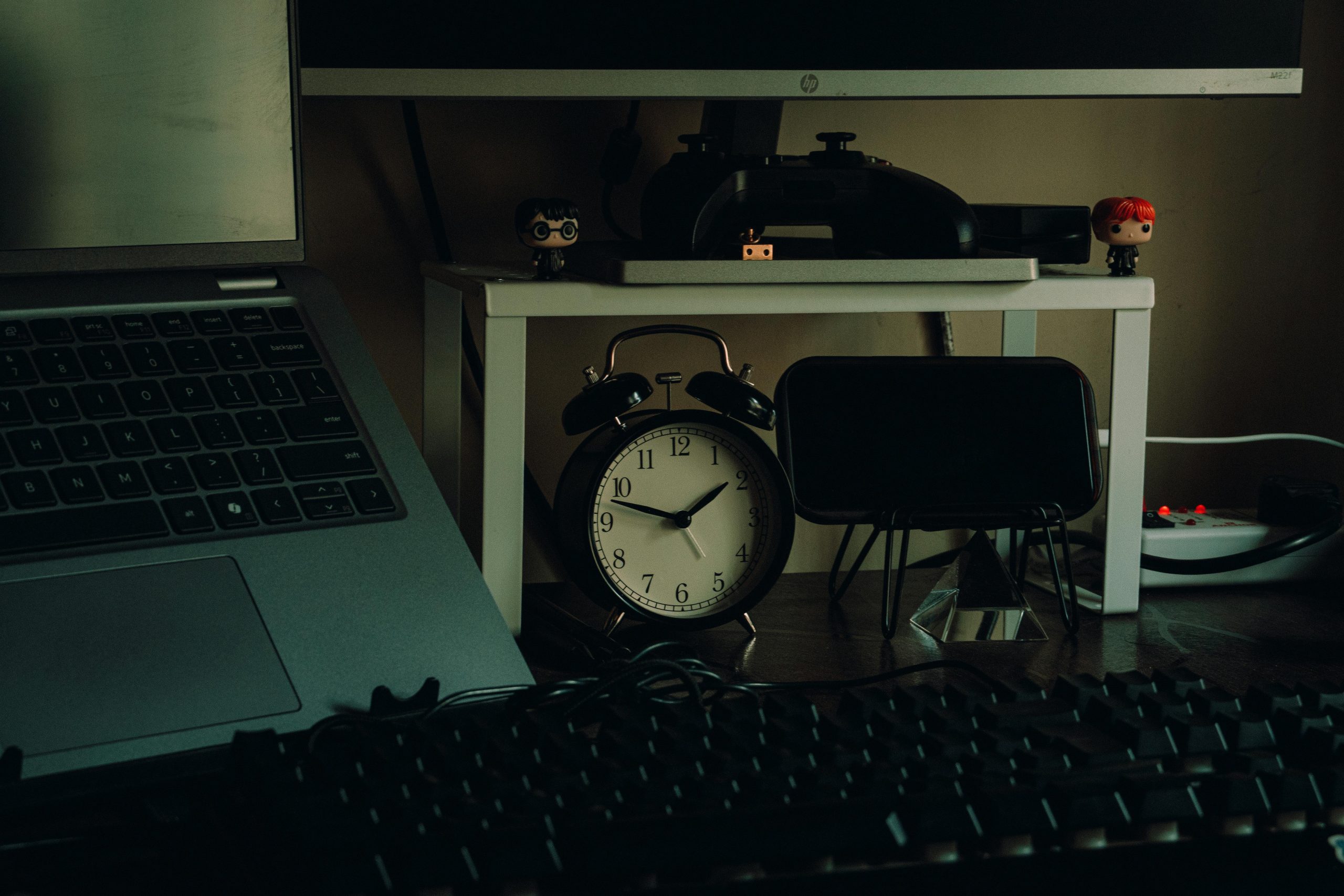 Tidy desk setup with a laptop, analog clock, and desk decor in a modern home workspace setting.