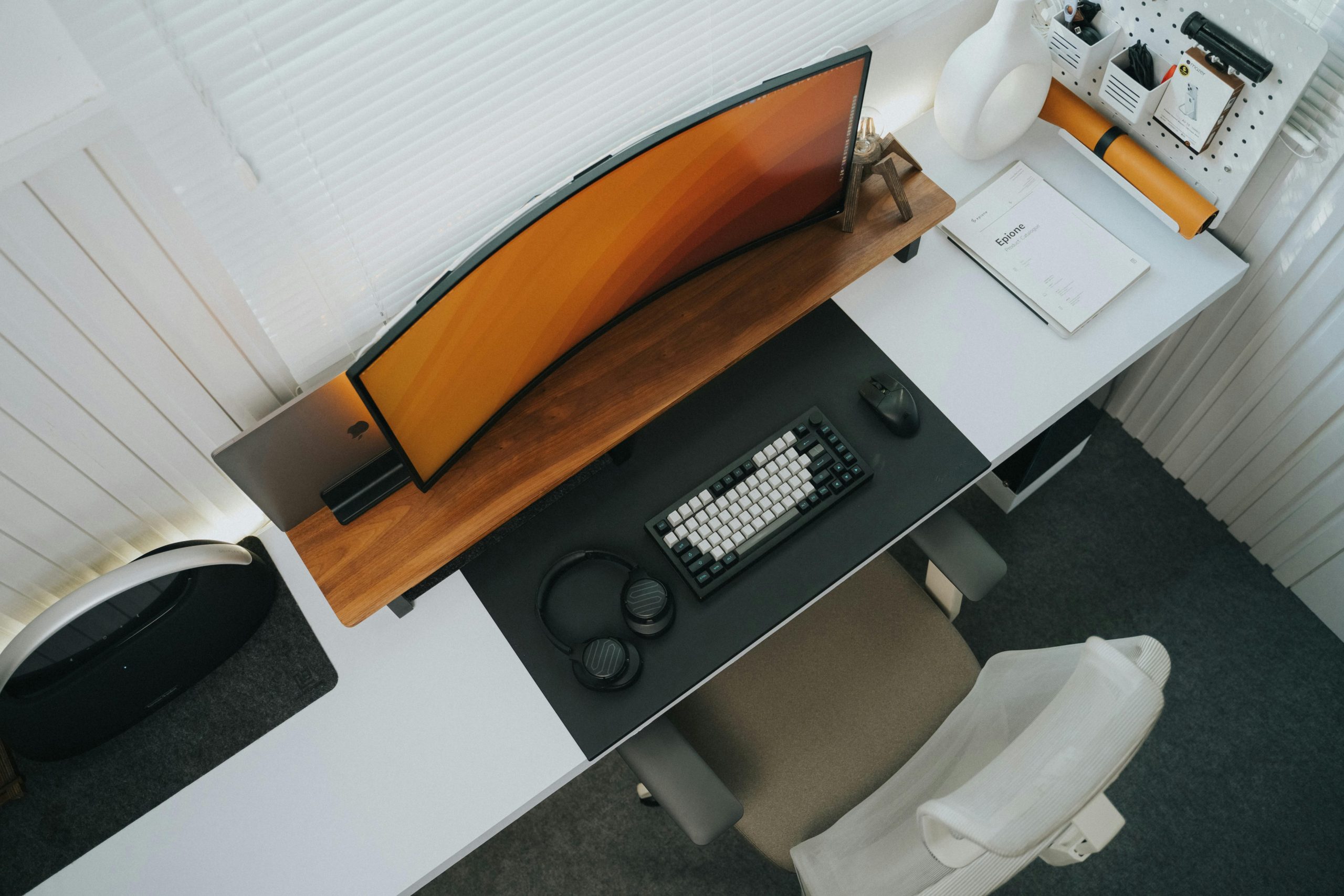 Top view of a stylish modern office desk setup featuring a curved monitor and keyboard.