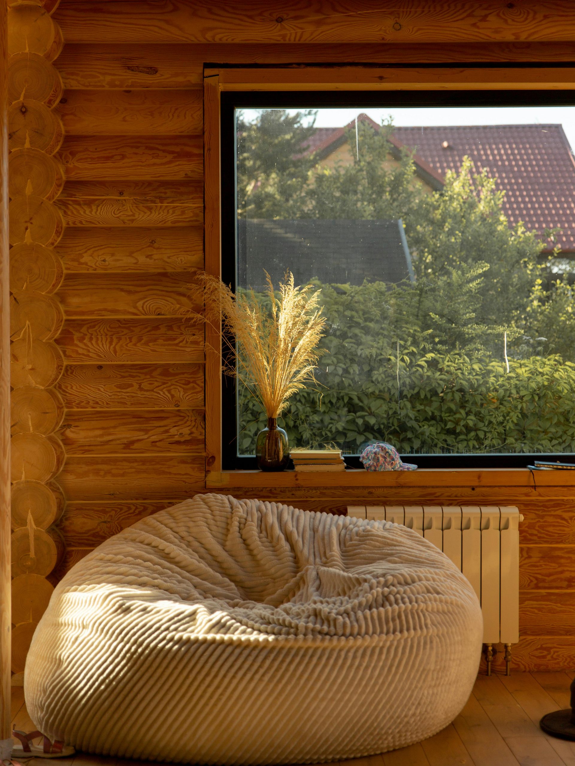 Warm rustic living room featuring a comfy bean bag and large window with garden view.