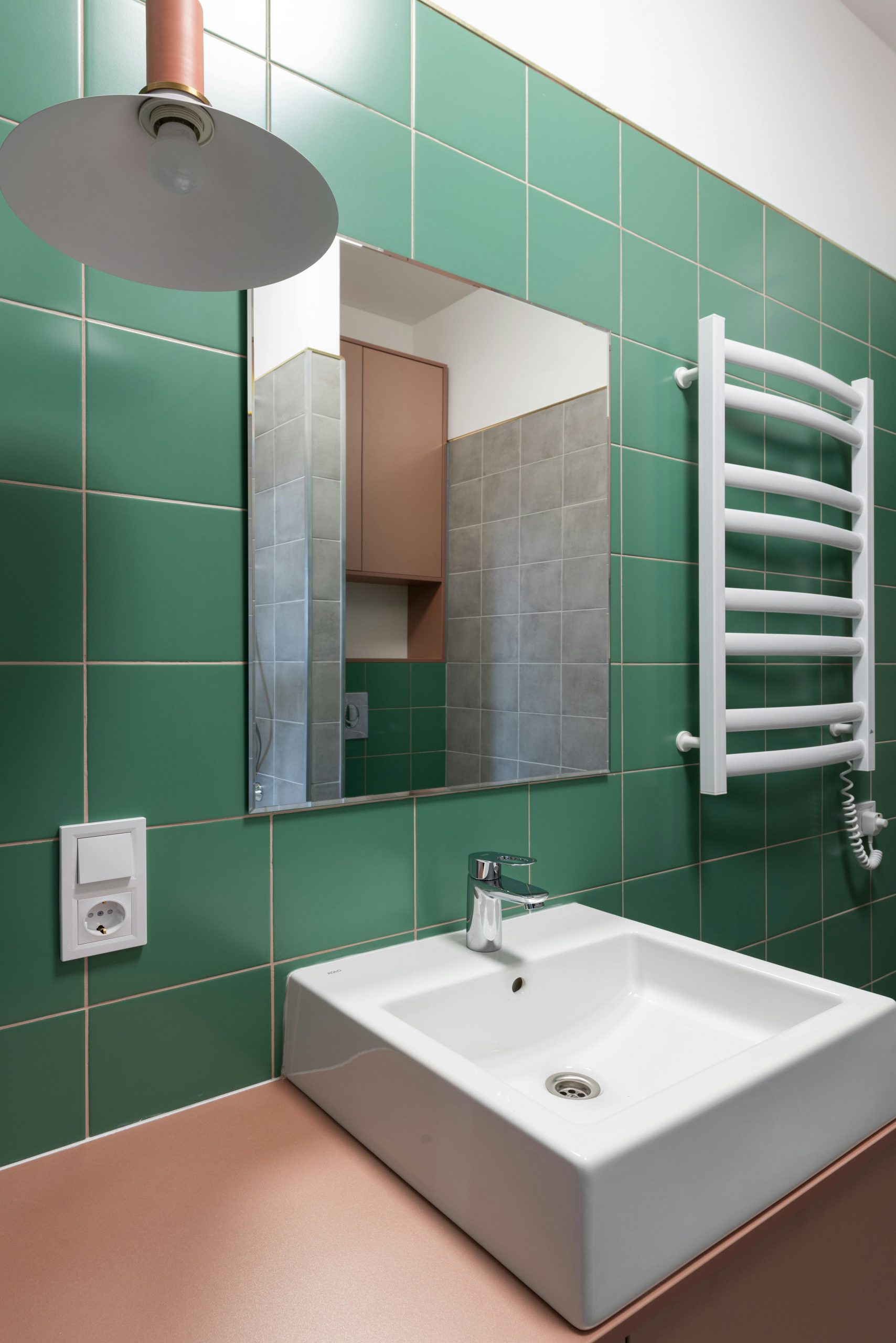 White ceramic sink on pink table and mirror on green wall in contemporary bathroom in new flat