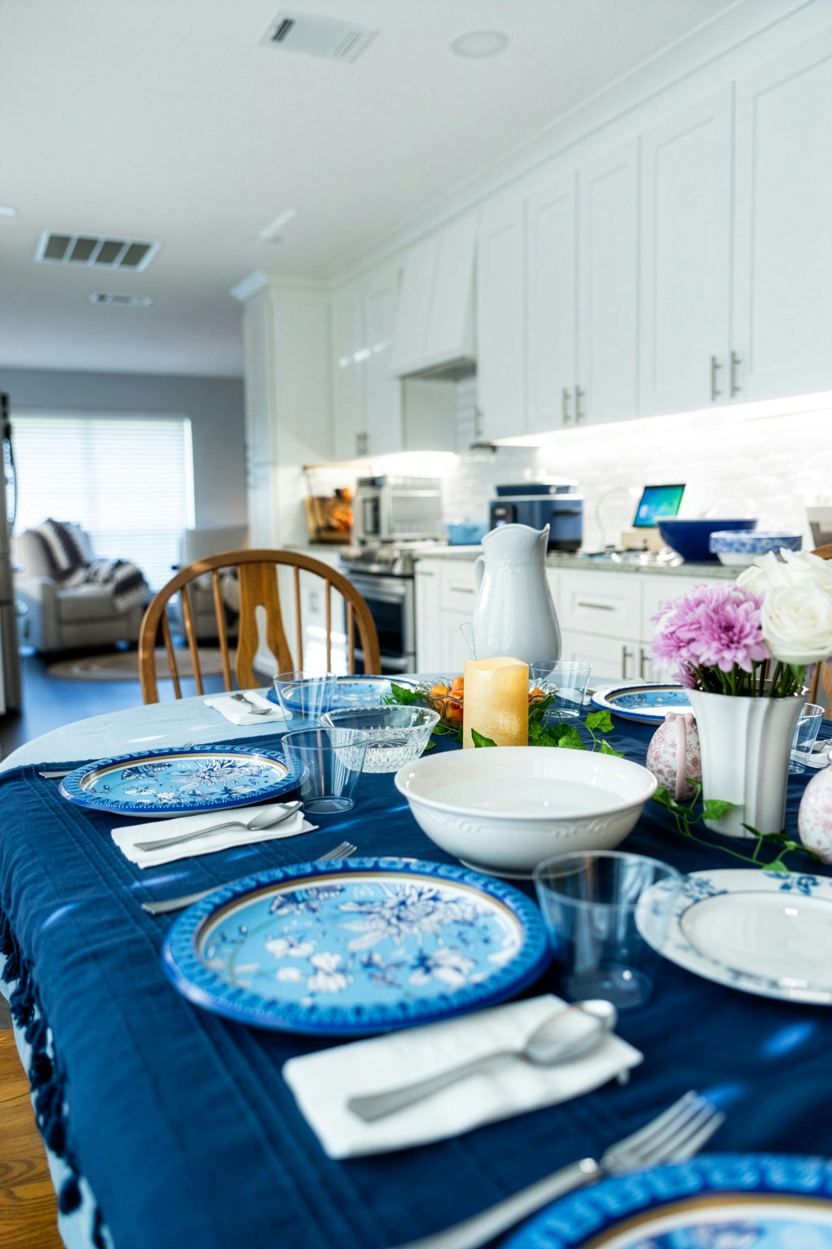 A beautifully set dining table with blue dinnerware and floral decor in a modern kitchen.