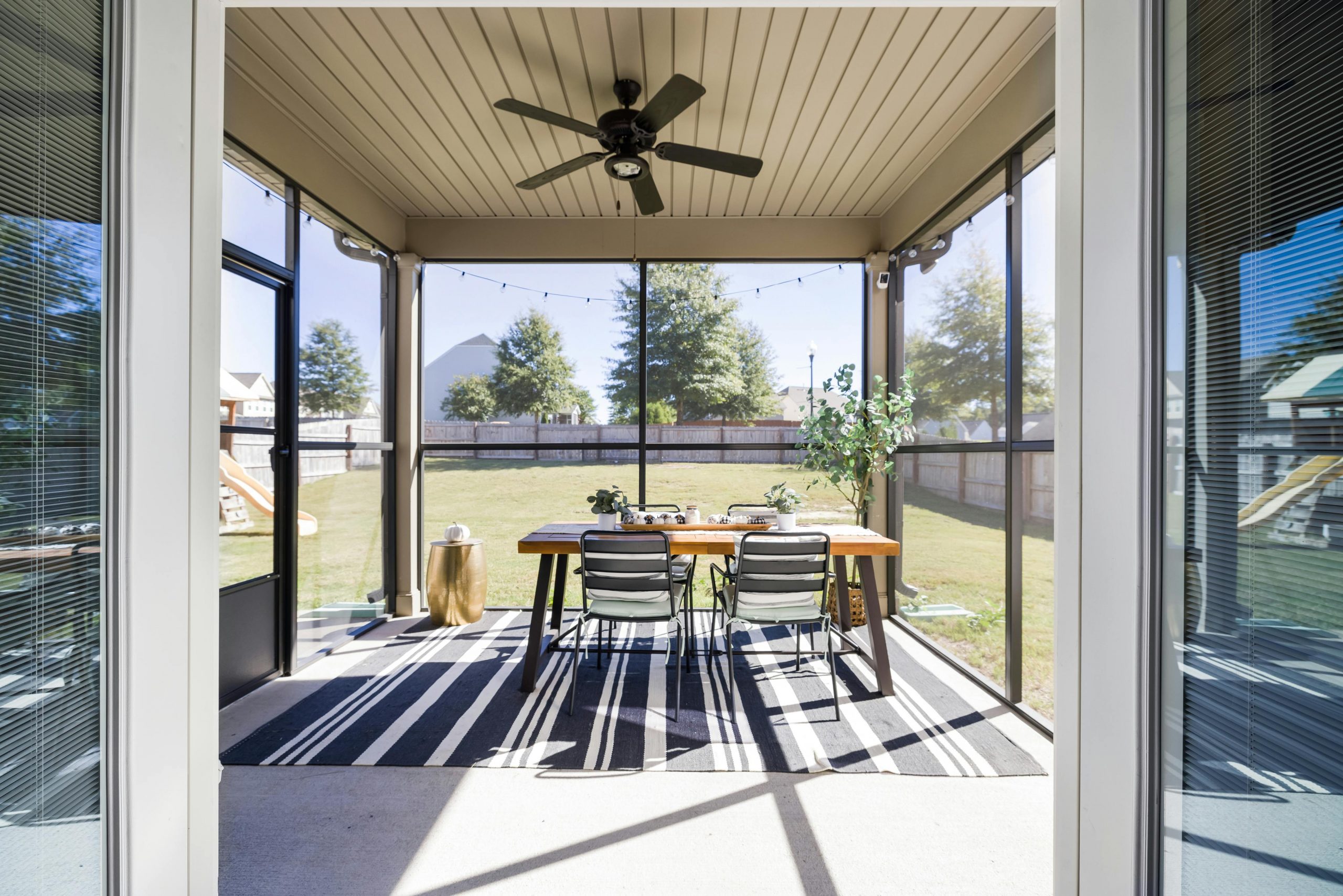 A bright and inviting terrace with dining table and chairs, overlooking a sunny garden.