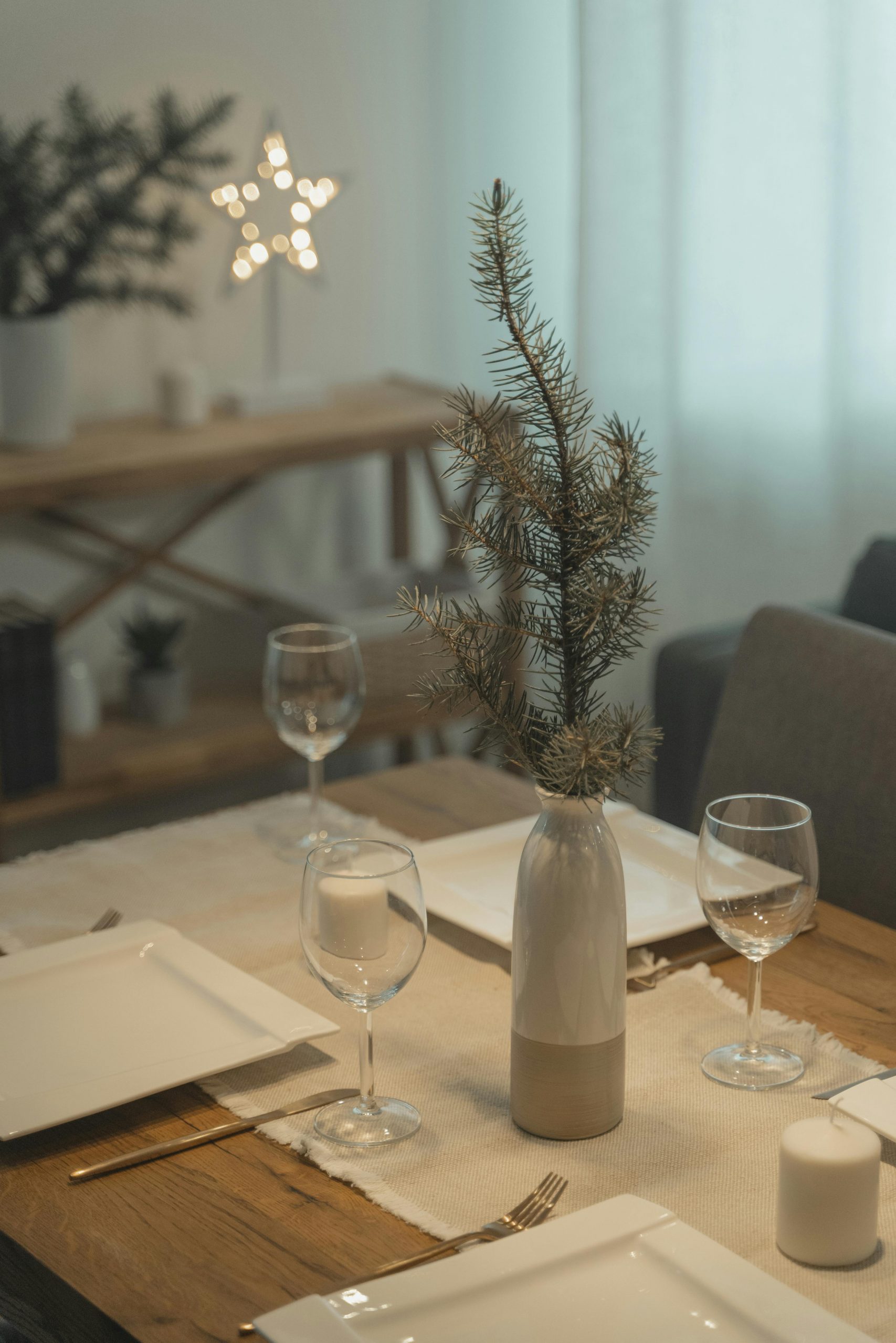 A cozy and elegant rustic table setting featuring pine branches and ceramic tableware.