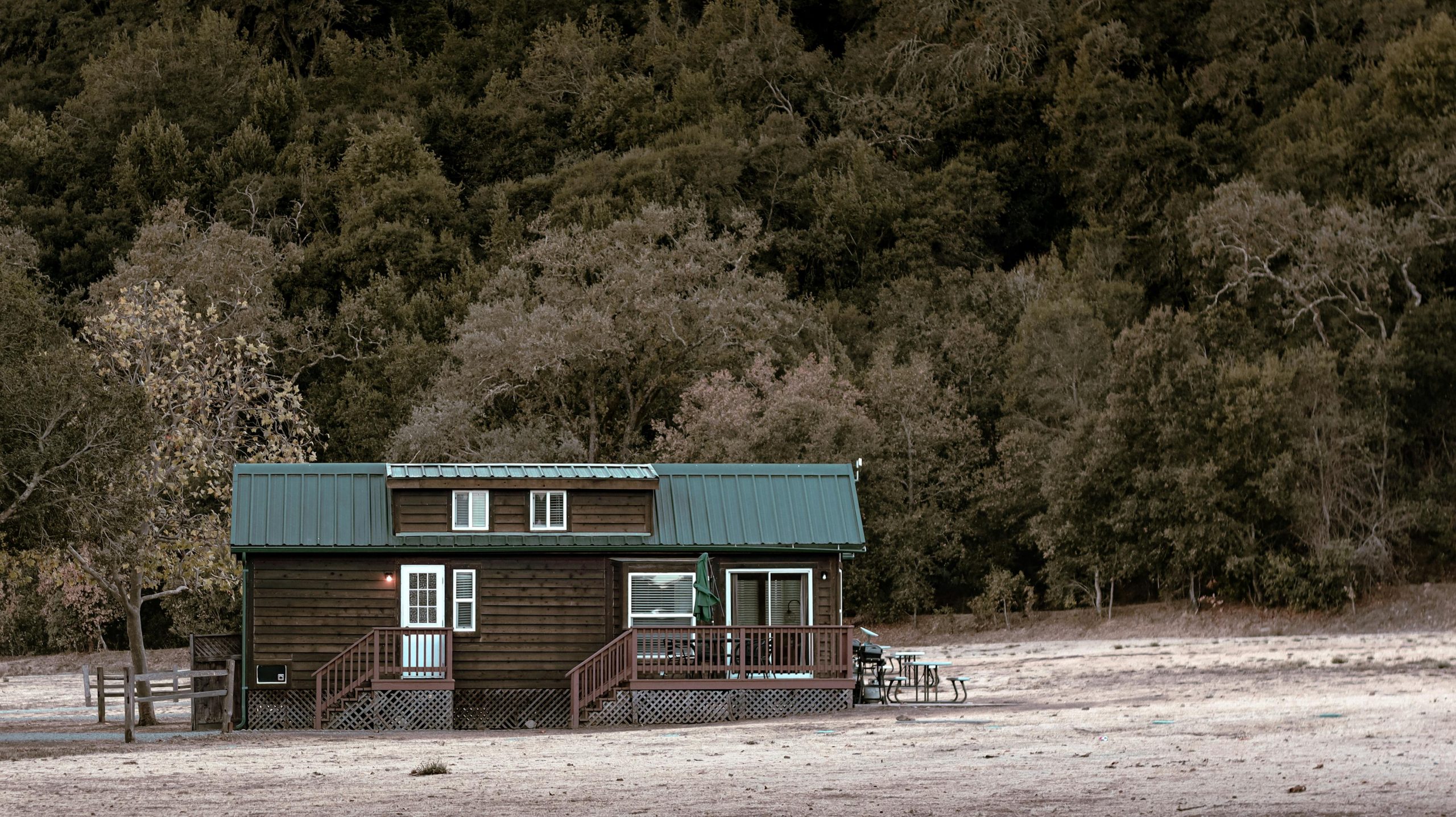A quaint wooden cabin nestled in a tranquil forested area, ideal for solitude.