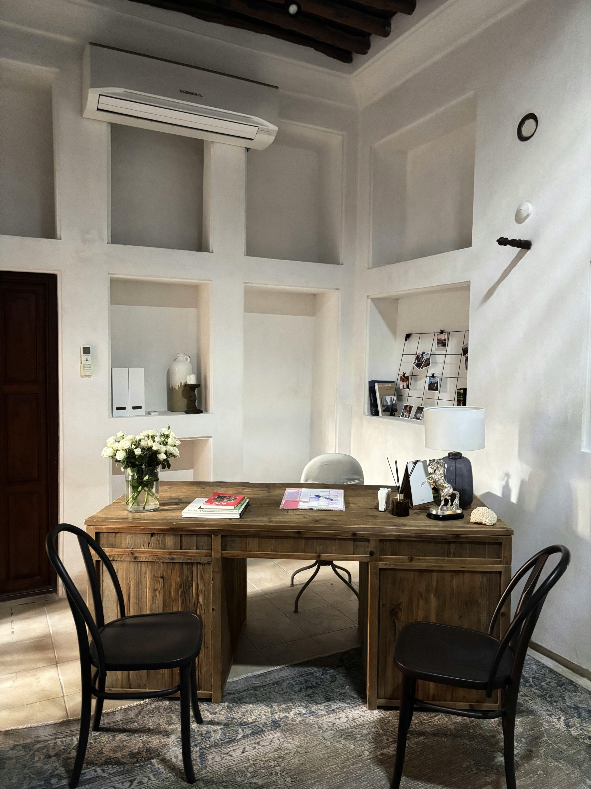 A serene and stylish office space with a wooden desk, chairs, and natural decor elements.