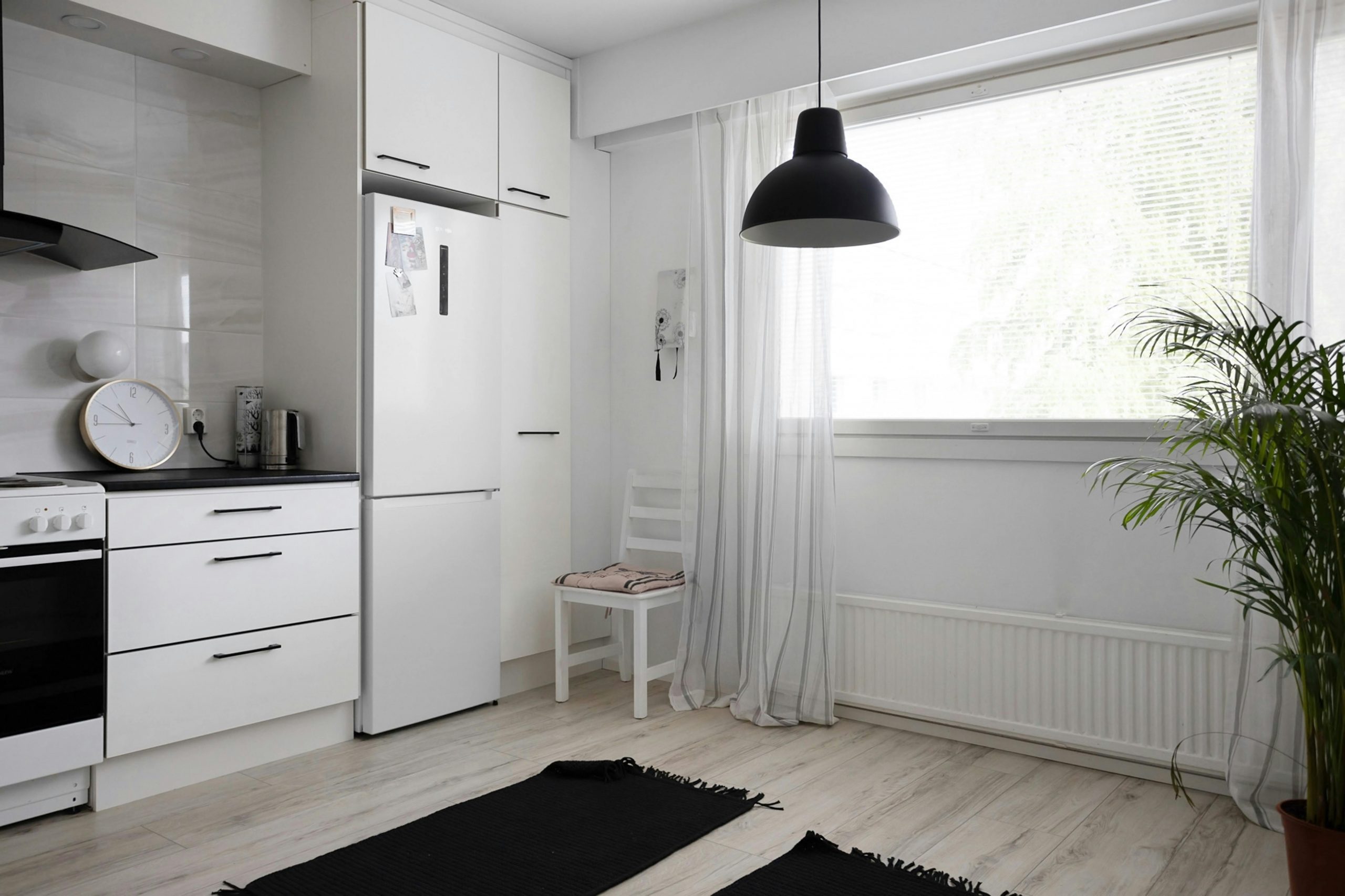 A sleek, minimalist kitchen featuring white cabinets, large window, and modern decor for a bright interior design.