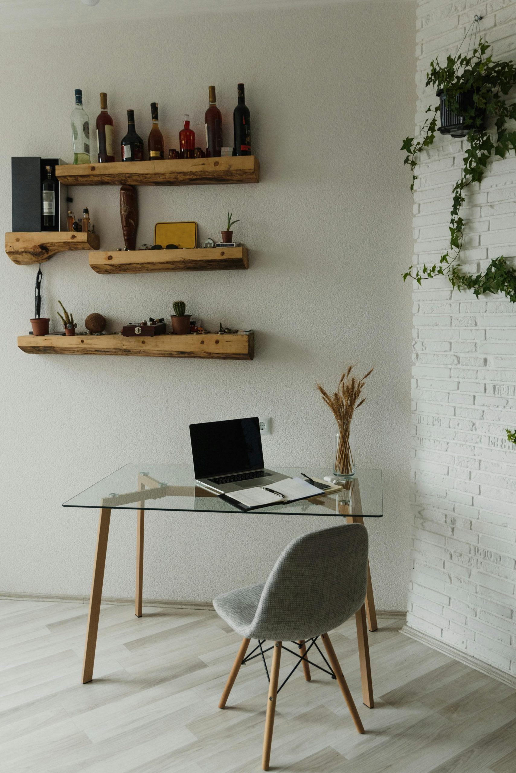 A stylish home workspace featuring wooden shelves and a minimalist glass desk.