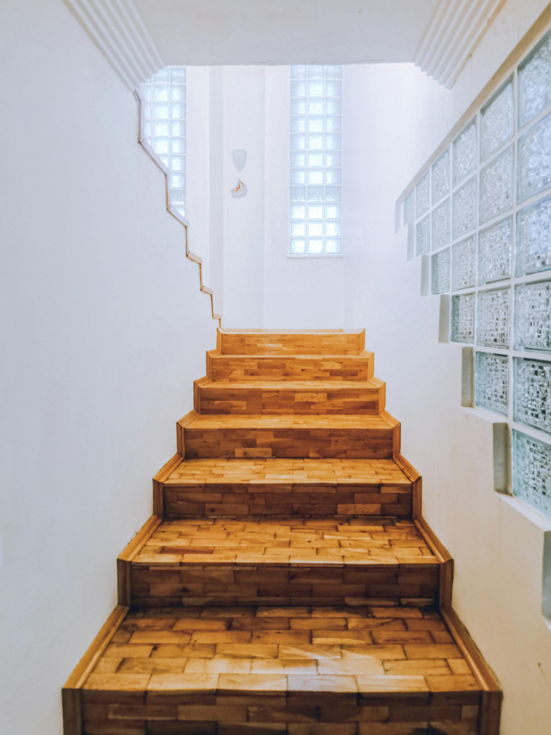 A stylish wooden staircase with glass block walls in a contemporary interior setting.