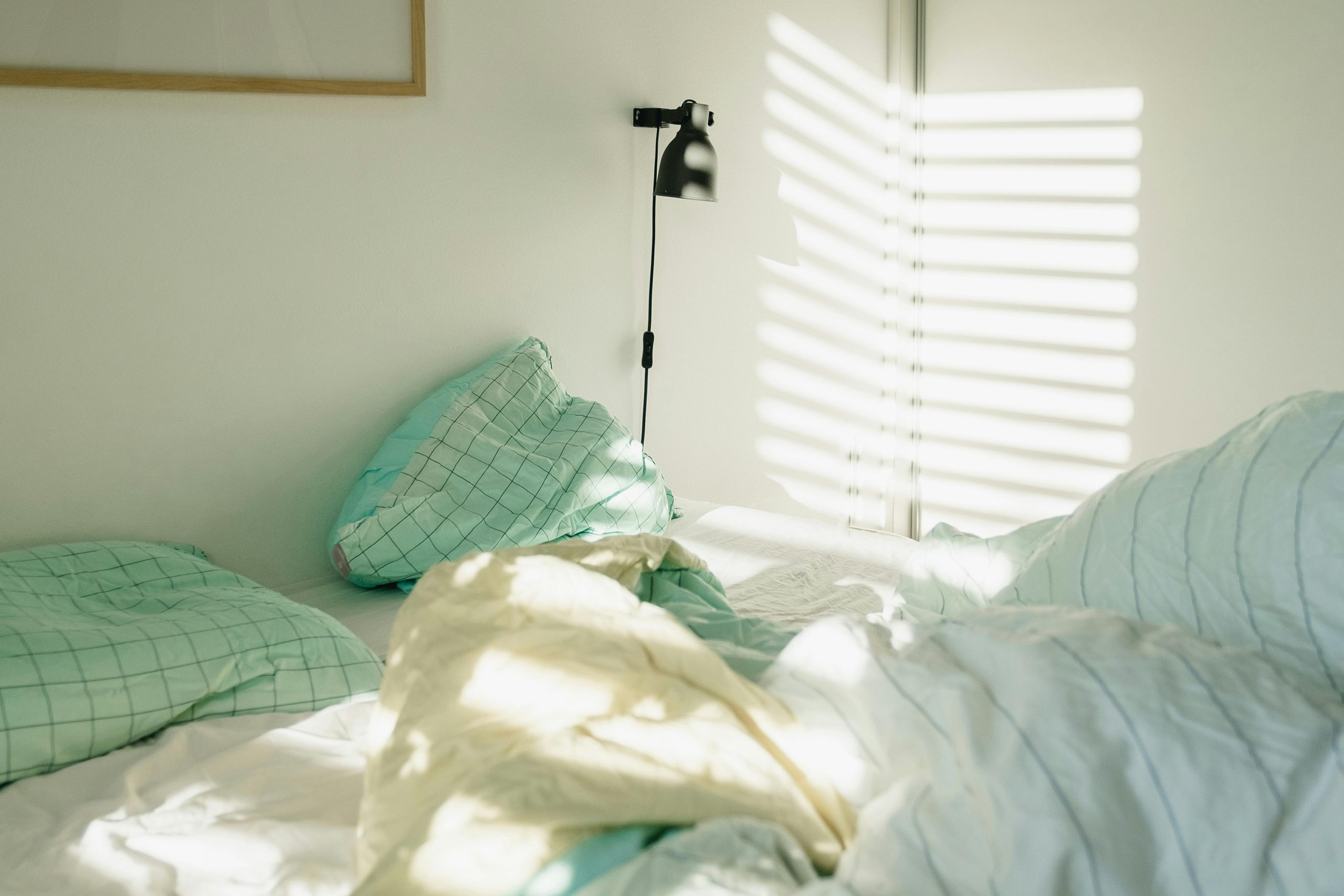 A sunlit Scandinavian-style bed with soft pillows and blankets, evoking a cozy morning in Copenhagen.