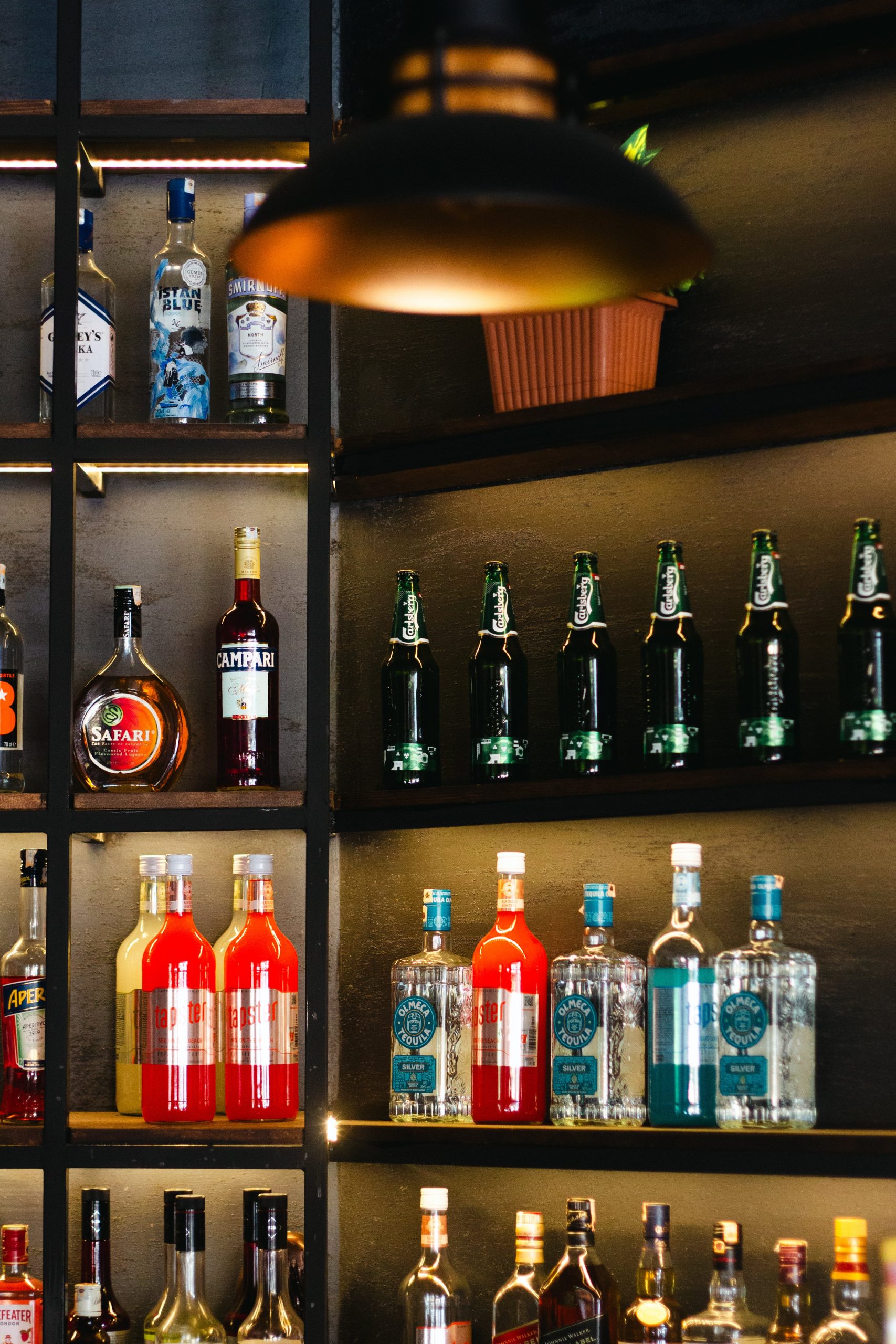 A vibrant display of assorted liquor bottles on bar shelves with warm lighting.