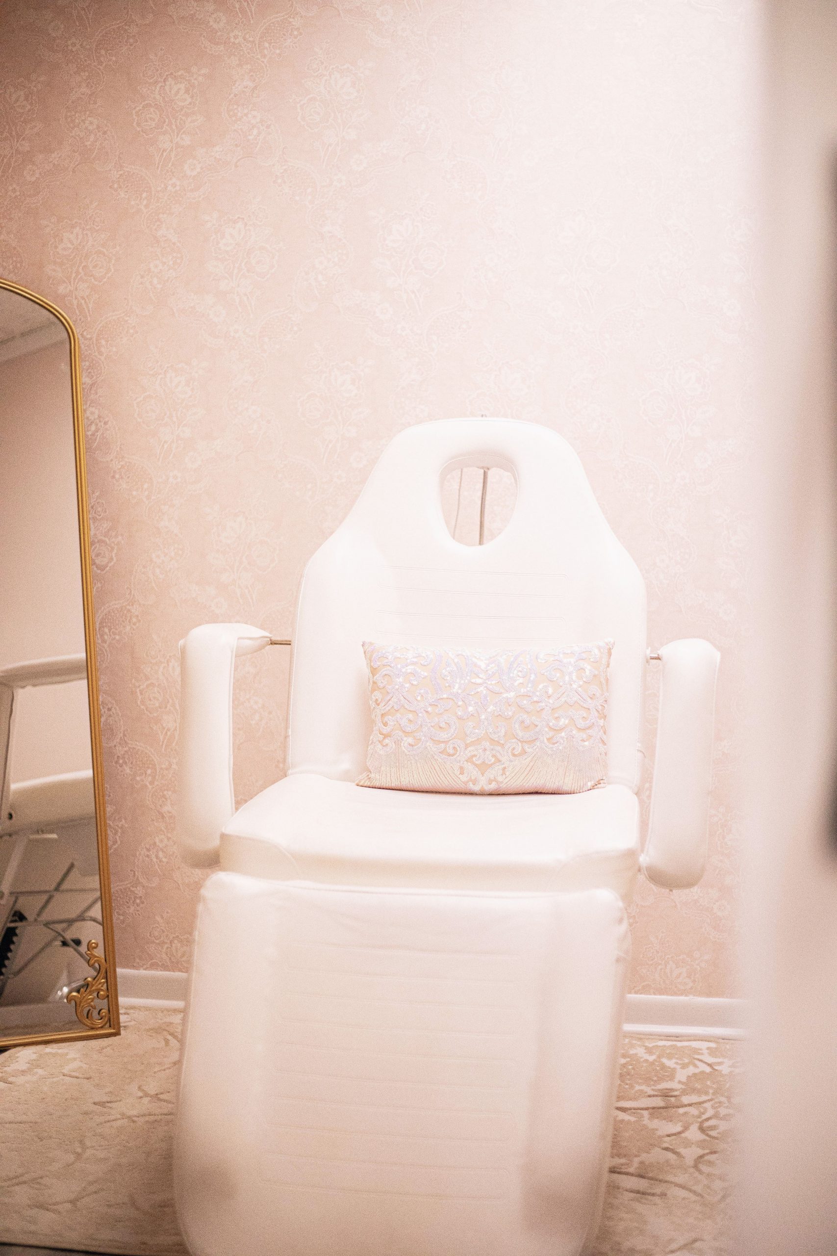 An elegant spa chair in a modern, minimalist wellness clinic with soft pink tones.