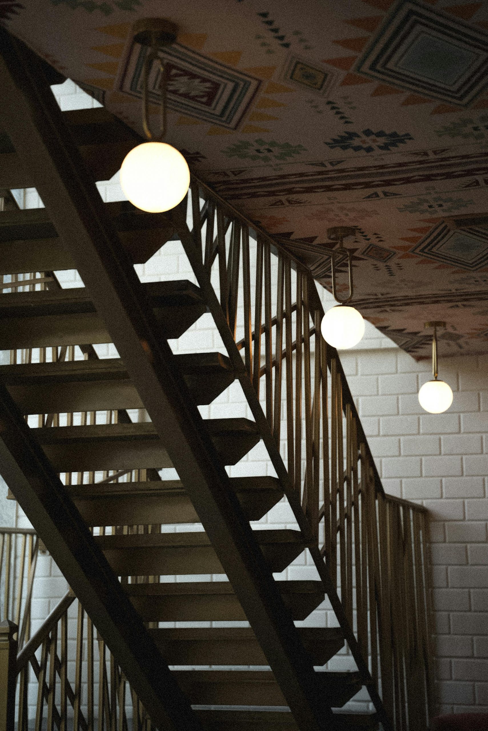 Artistic view of a staircase with unique railings and round ceiling lights creating a modern feel.
