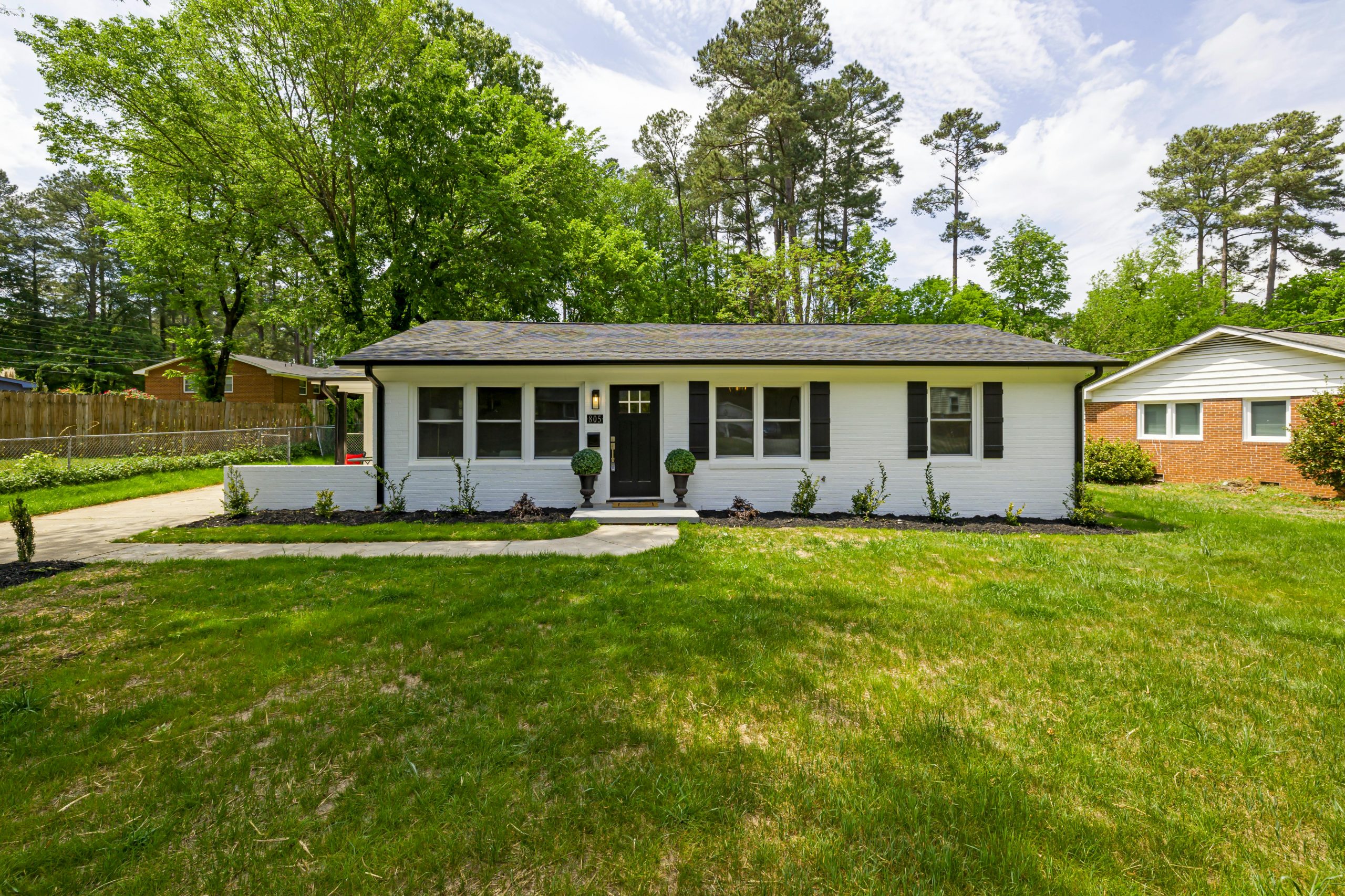 Beautiful single-story suburban house with a front lawn and surrounding trees.