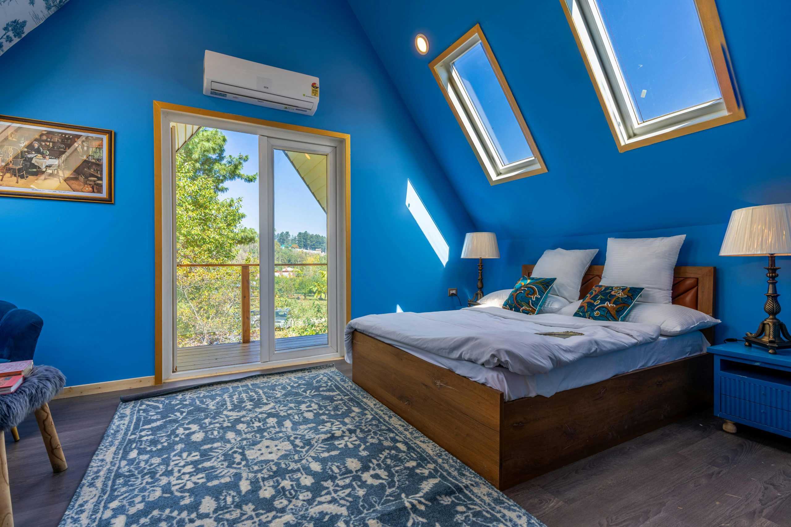Bright attic bedroom with skylights, blue walls, and cozy decor.