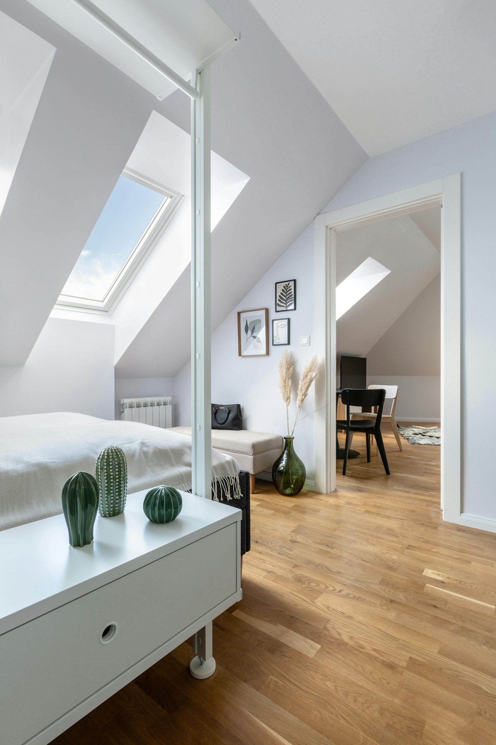 Bright, modern attic bedroom with skylight in Prague apartment, featuring minimalist decor.