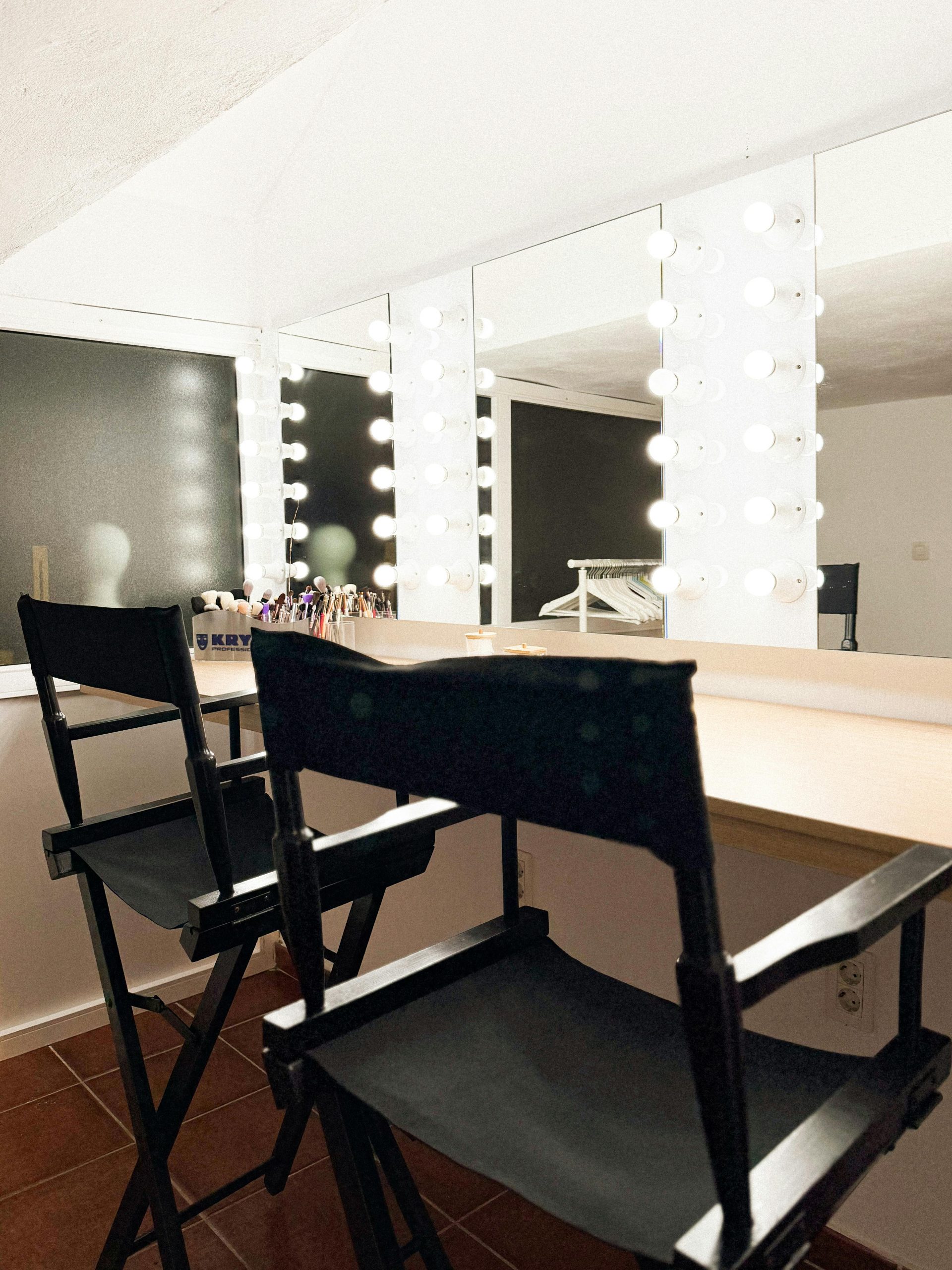 Bright, stylish makeup studio interior featuring illuminated vanity mirrors and director chairs.
