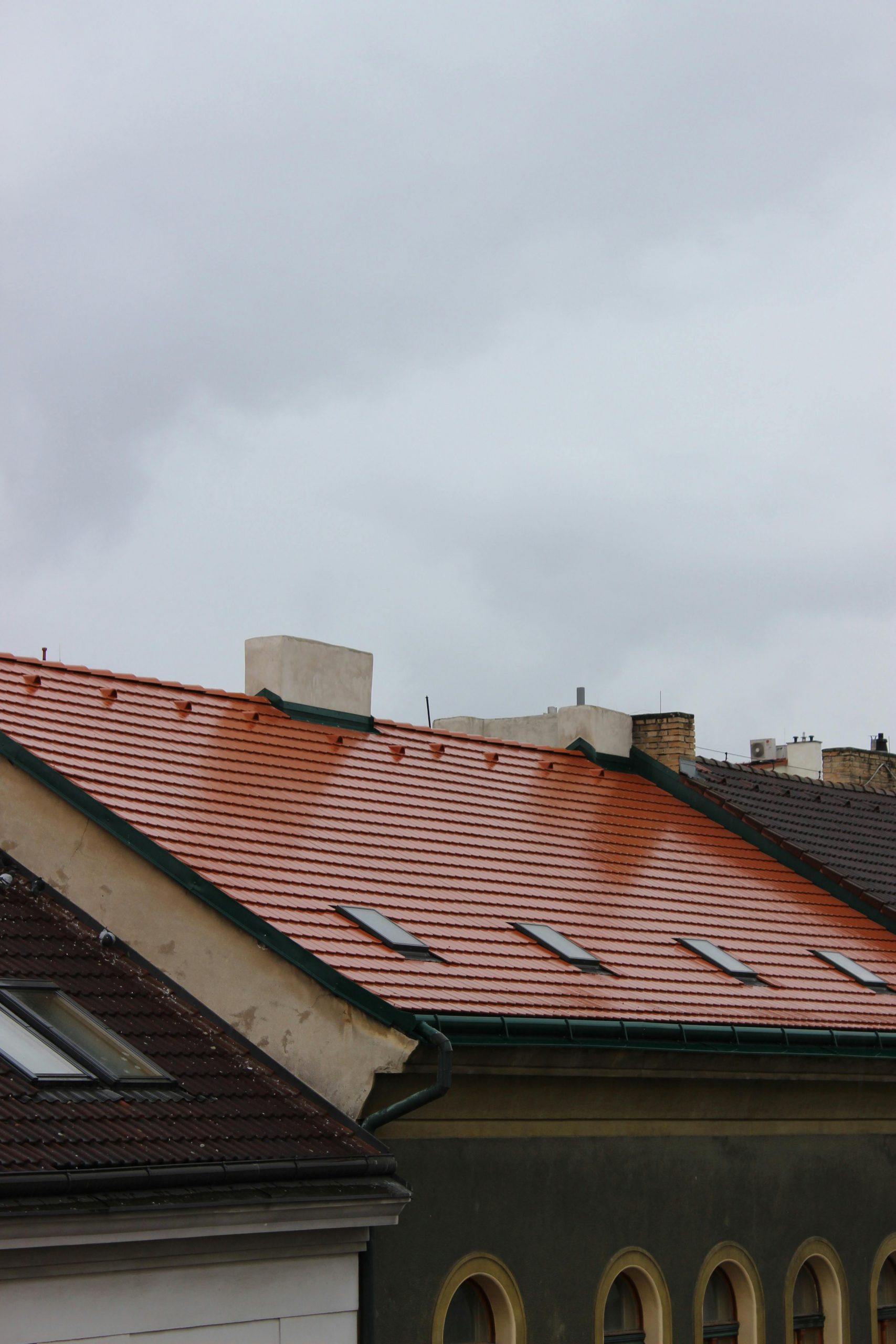 Capture of red tiled rooftops in an urban area under a cloudy, rainy sky, evoking a moody atmosphere.