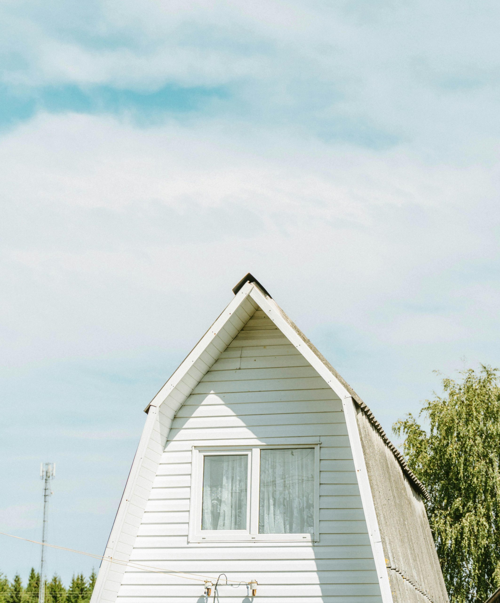 Charming A-frame cottage against a clear sky in the rural landscape of Vitebsk, Belarus.