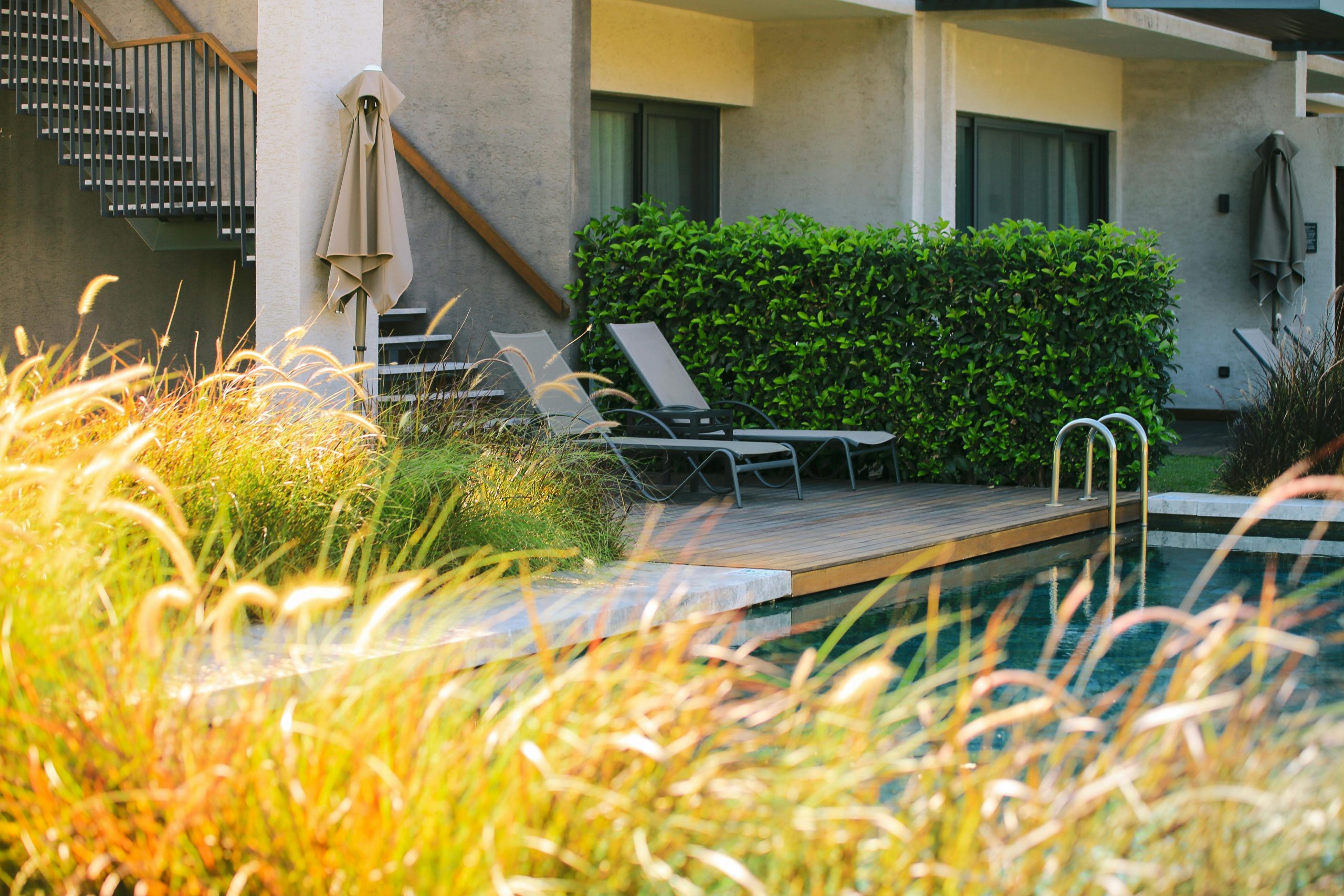 Chic poolside area with lounge chairs and lush greenery, ideal for relaxation.