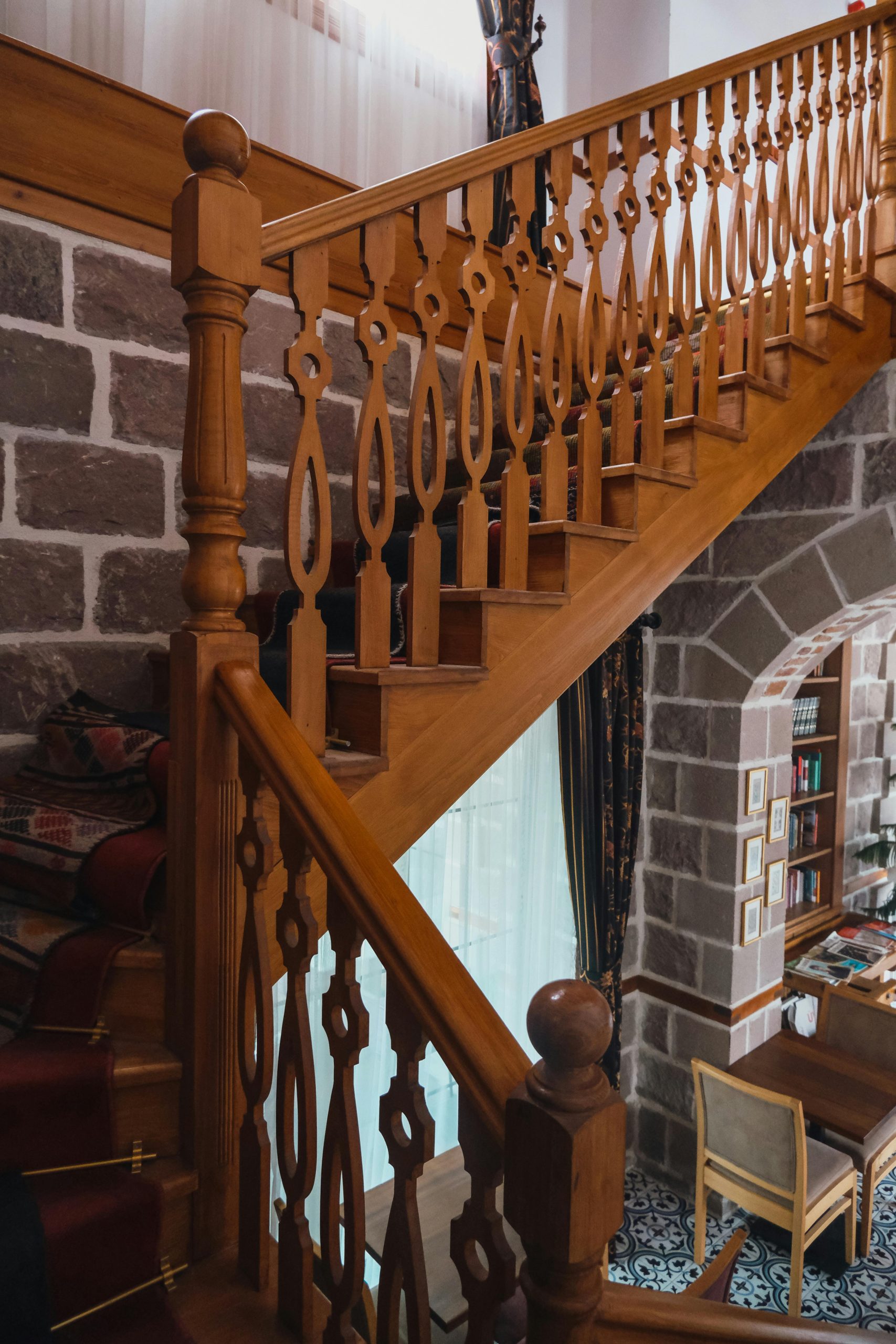 Close-up of an ornate wooden staircase with artistic handrail design in an indoor setting.