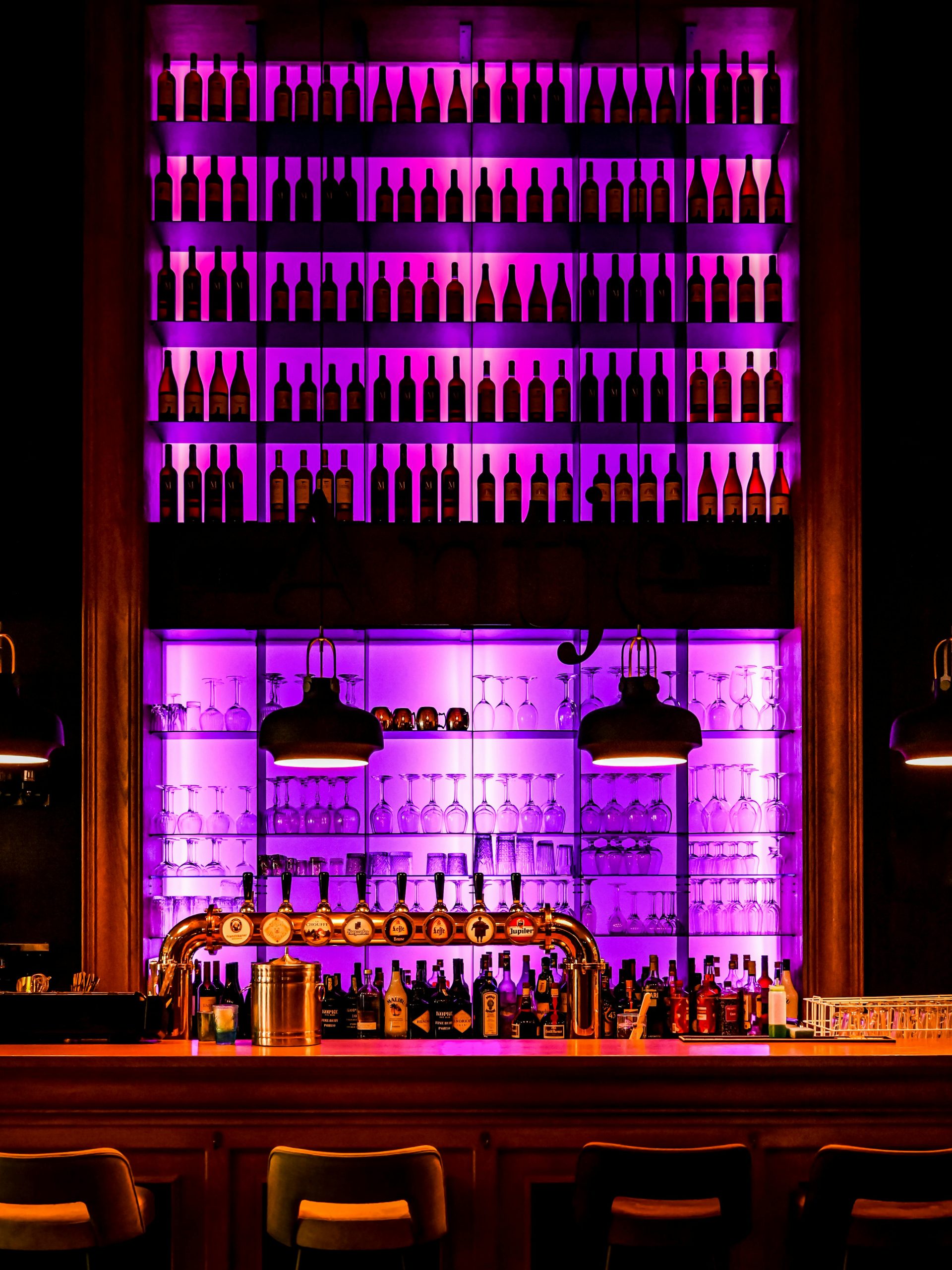 Contemporary bar setting with backlit shelves displaying bottles in Weert, Limburg.