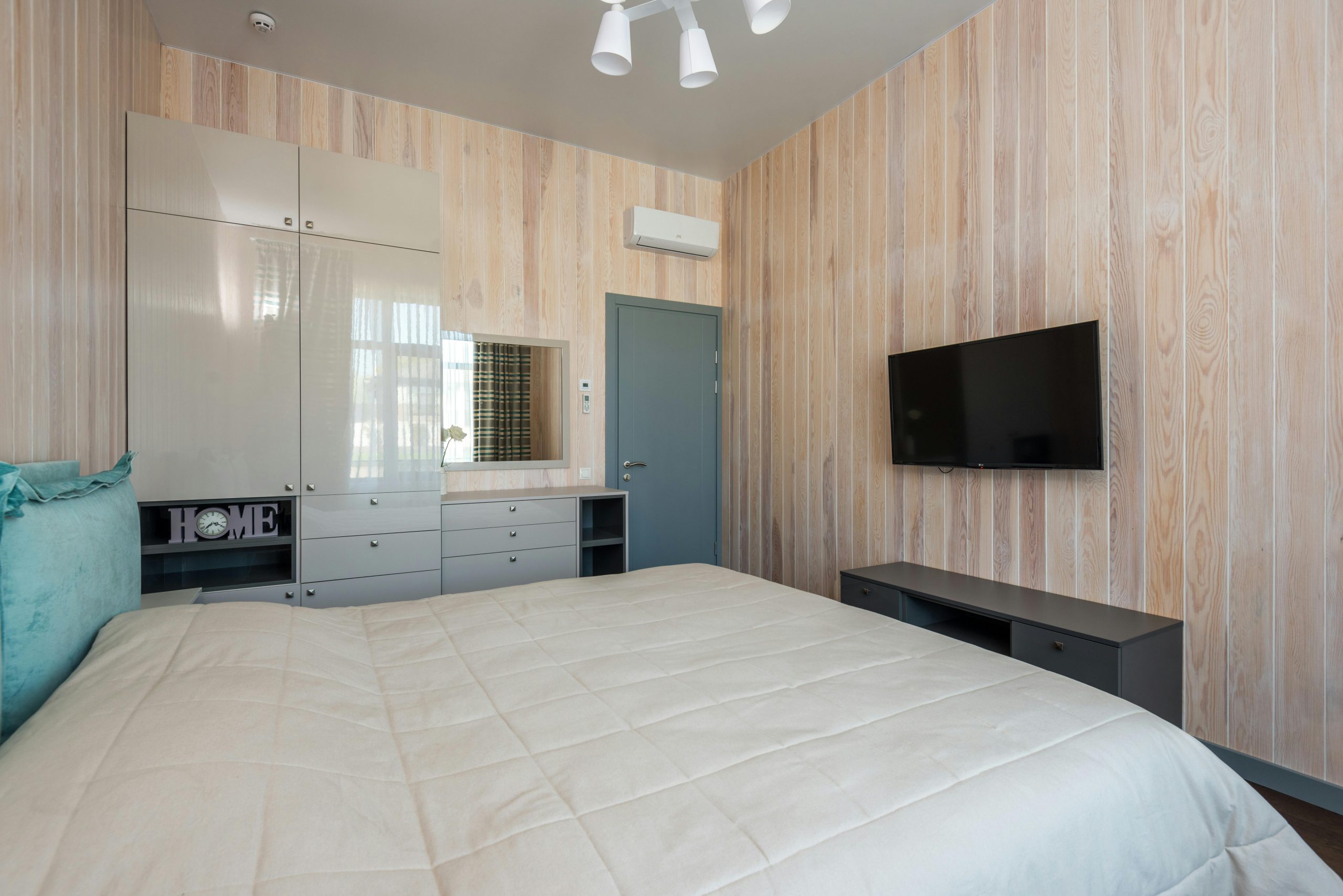 Contemporary bedroom featuring minimalist decor with wooden panel walls and a mounted TV.
