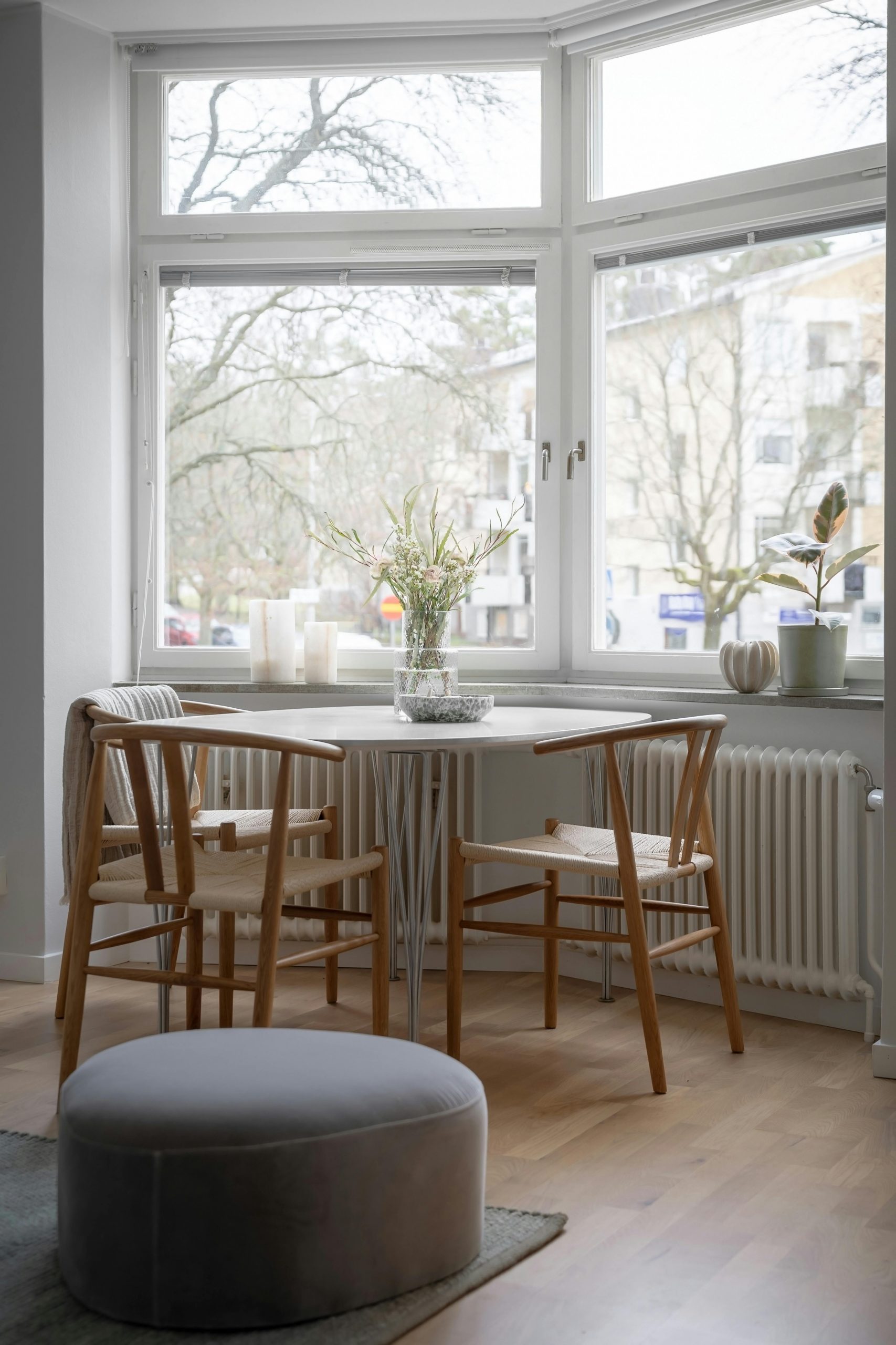 Cozy Scandinavian dining area with wooden chairs and large window.